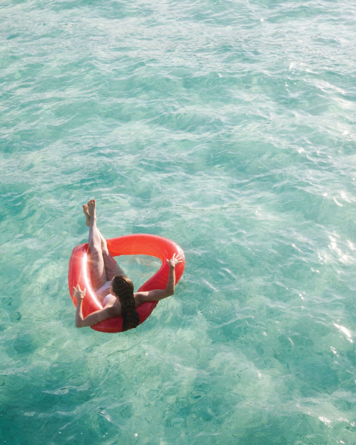 A woman is floating on a red pool inner tube in a body of water