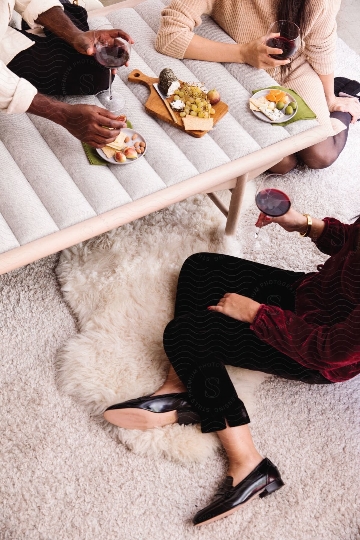 Three adults sitting together snacking and drinking wine