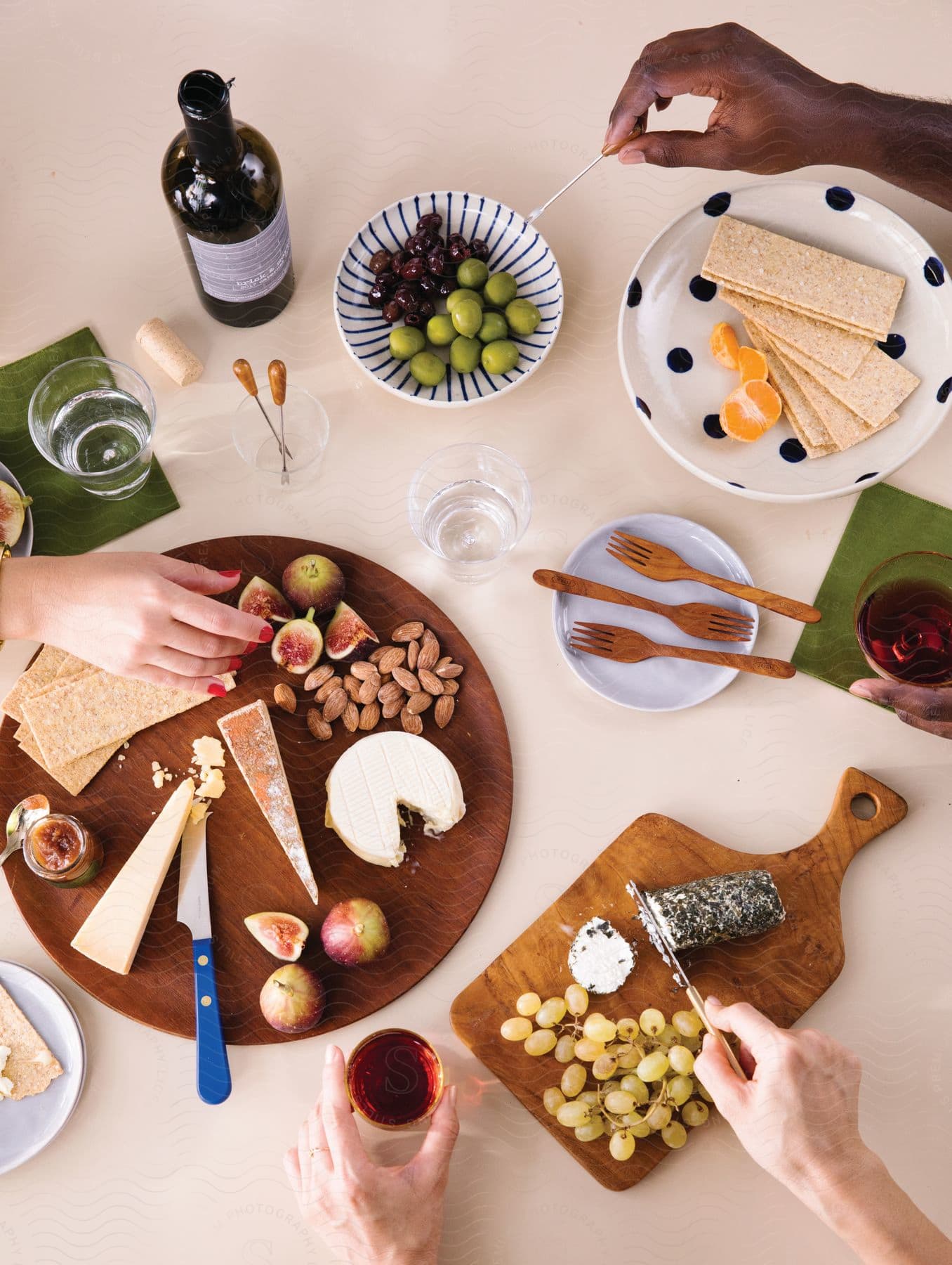 Friends enjoying a charcuterie spread with grapes cheese olives crackers figs and wine