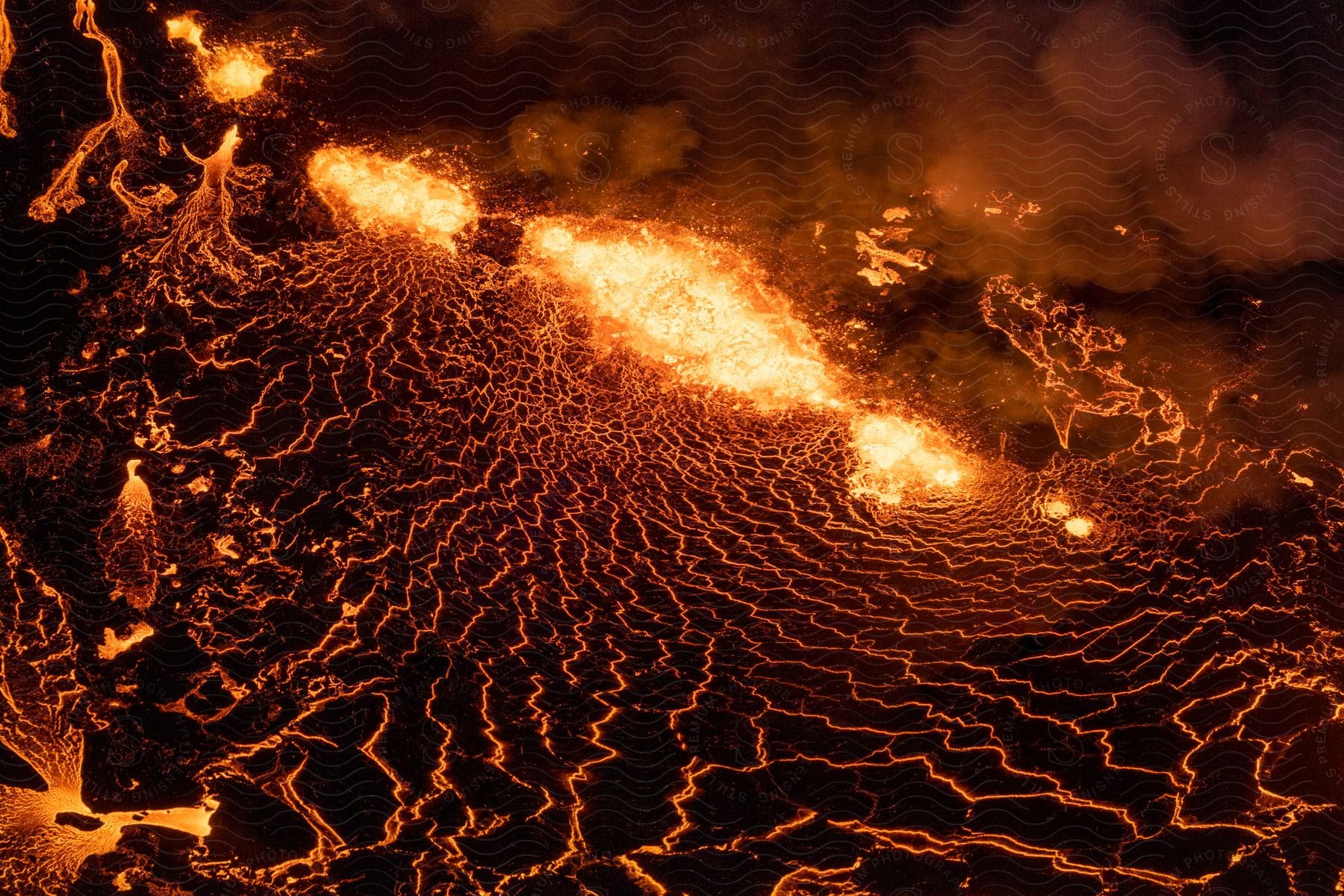 Lava erupting from a volcano and covering the ground at night
