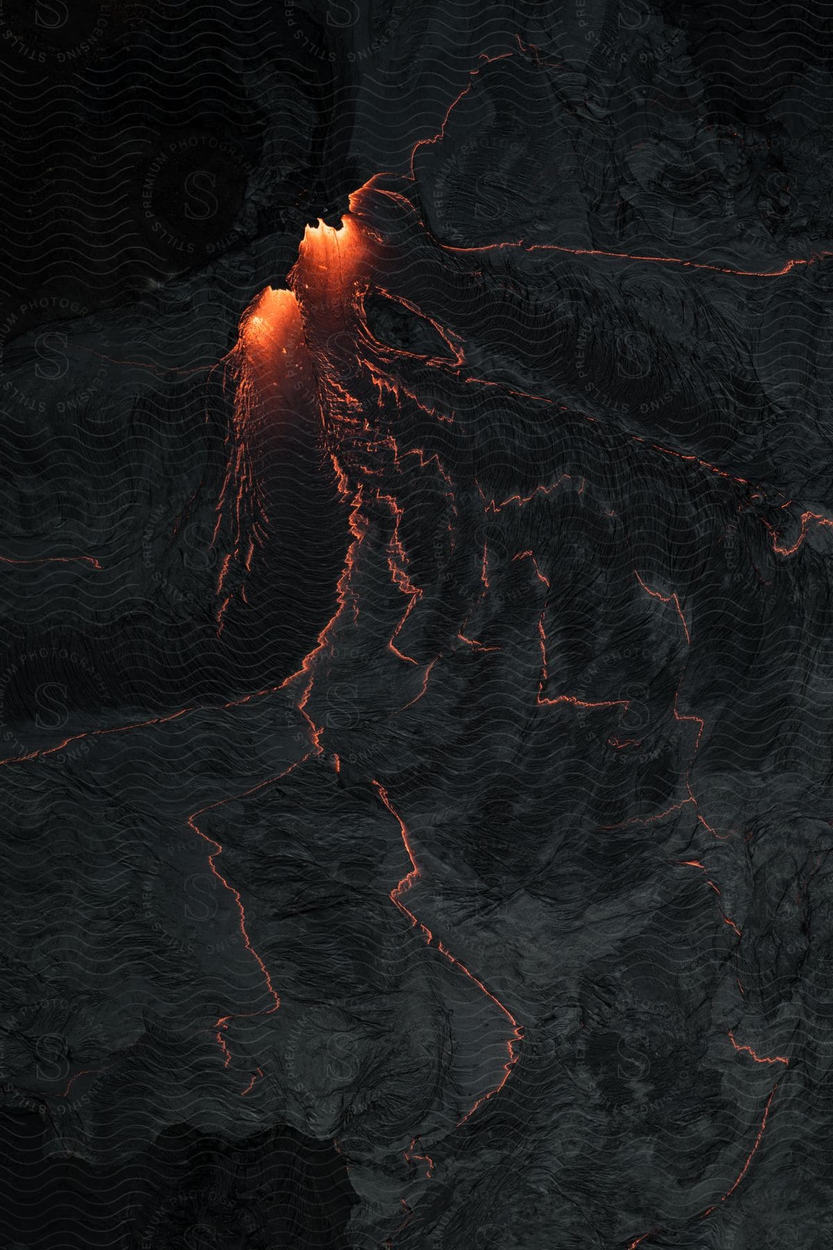 An aerial view of a volcano erupting over the land at night