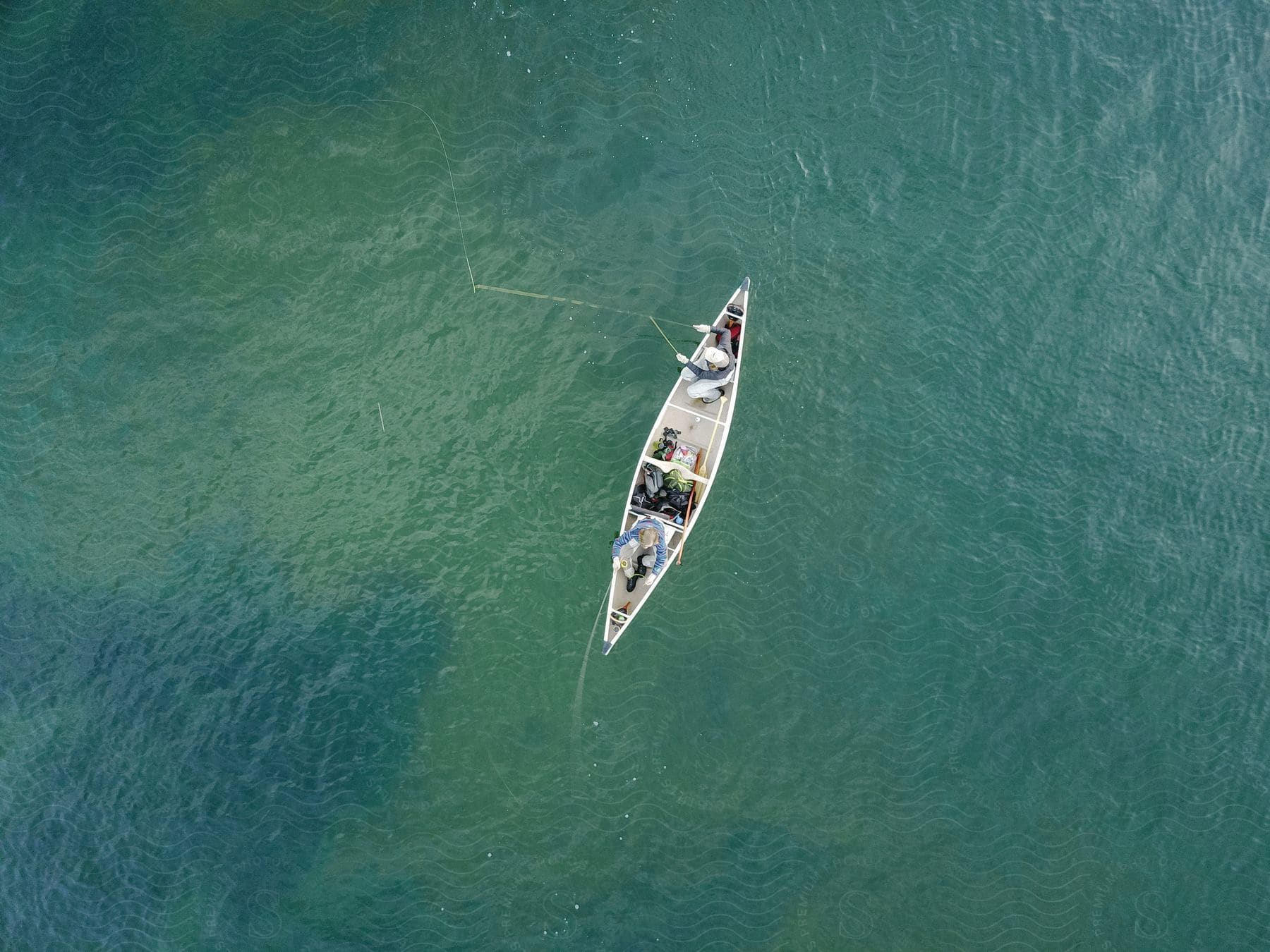 Two people are fishing from a canoe in the ocean