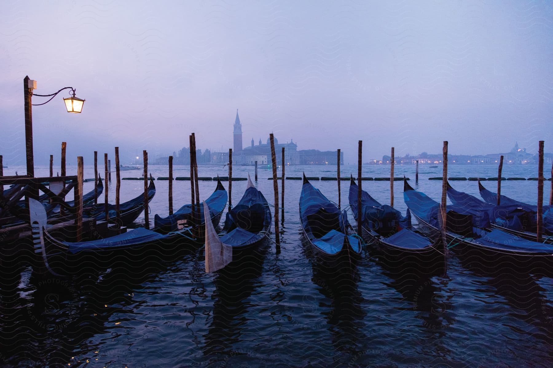 Small boats docked in the harbor with a city on the horizon beyond the water