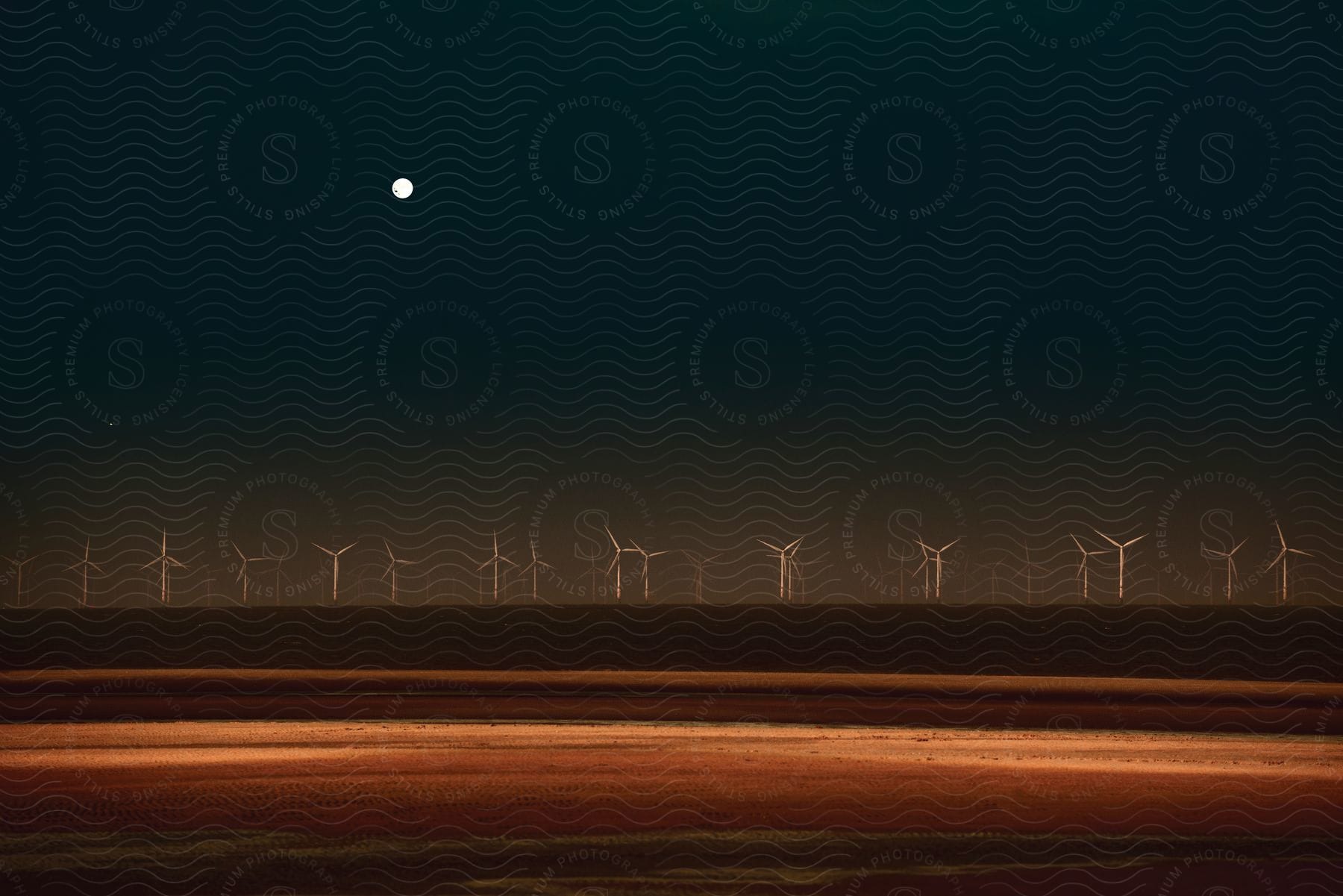 Full moon hangs in the night sky over wind farm