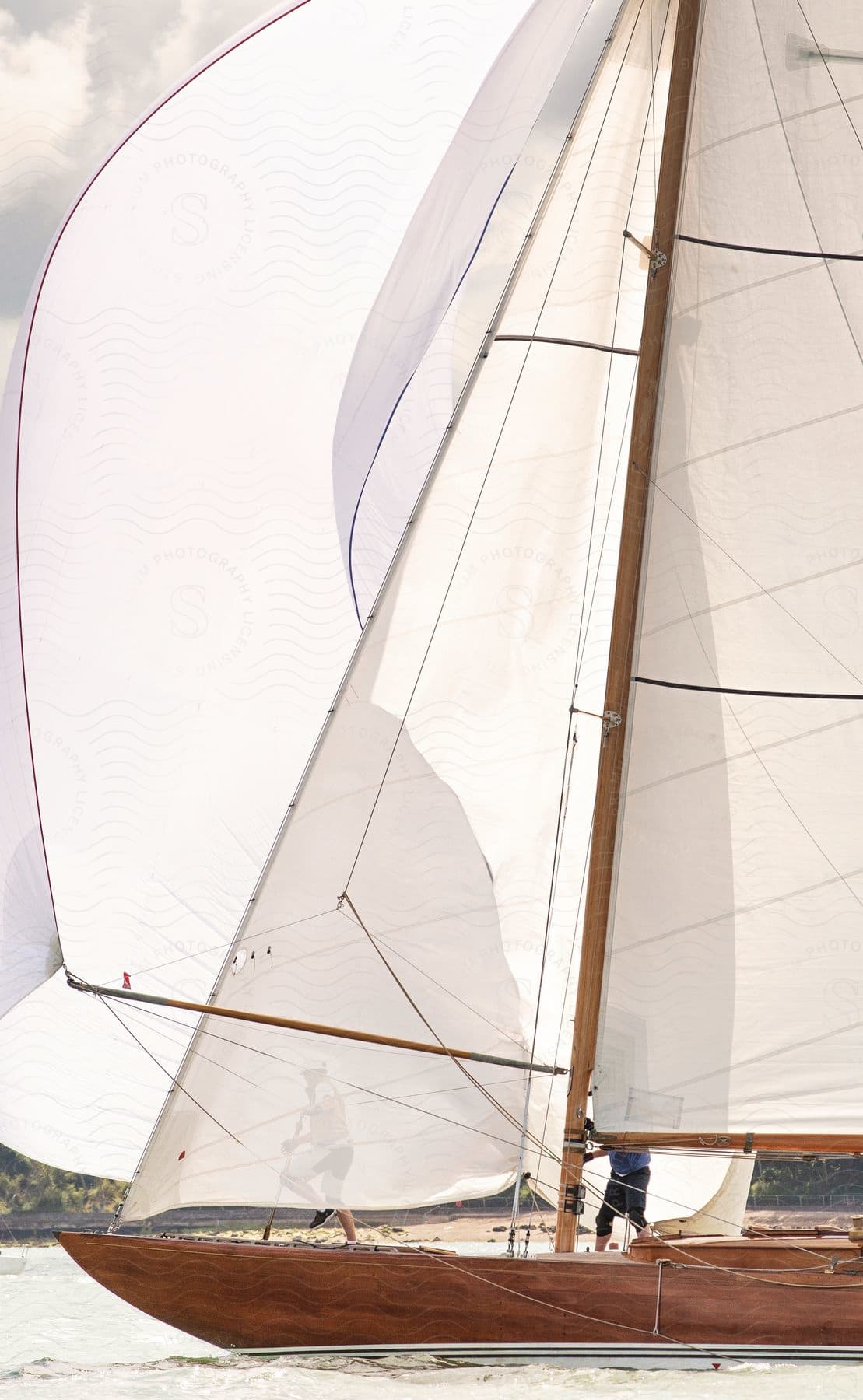 Two men stand on a sailing boat on the water