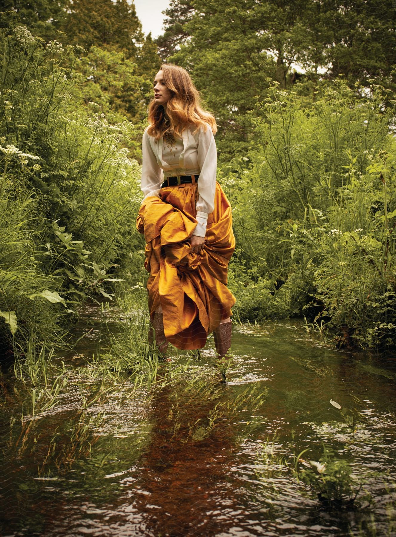 A person in nature wearing a skirt and standing near water