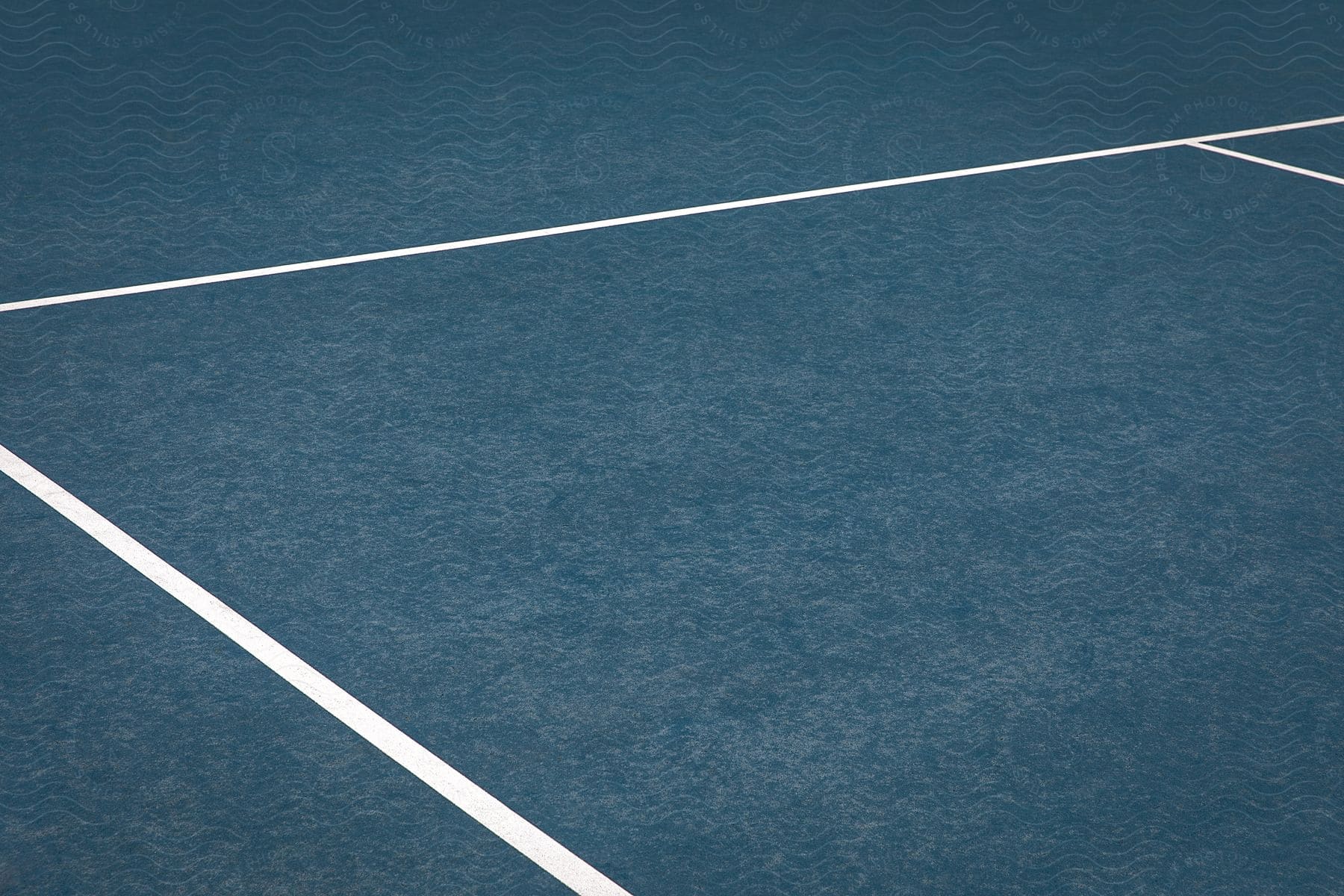 A closeup of the outofbounds line on a blue tennis court revealing the textured surface