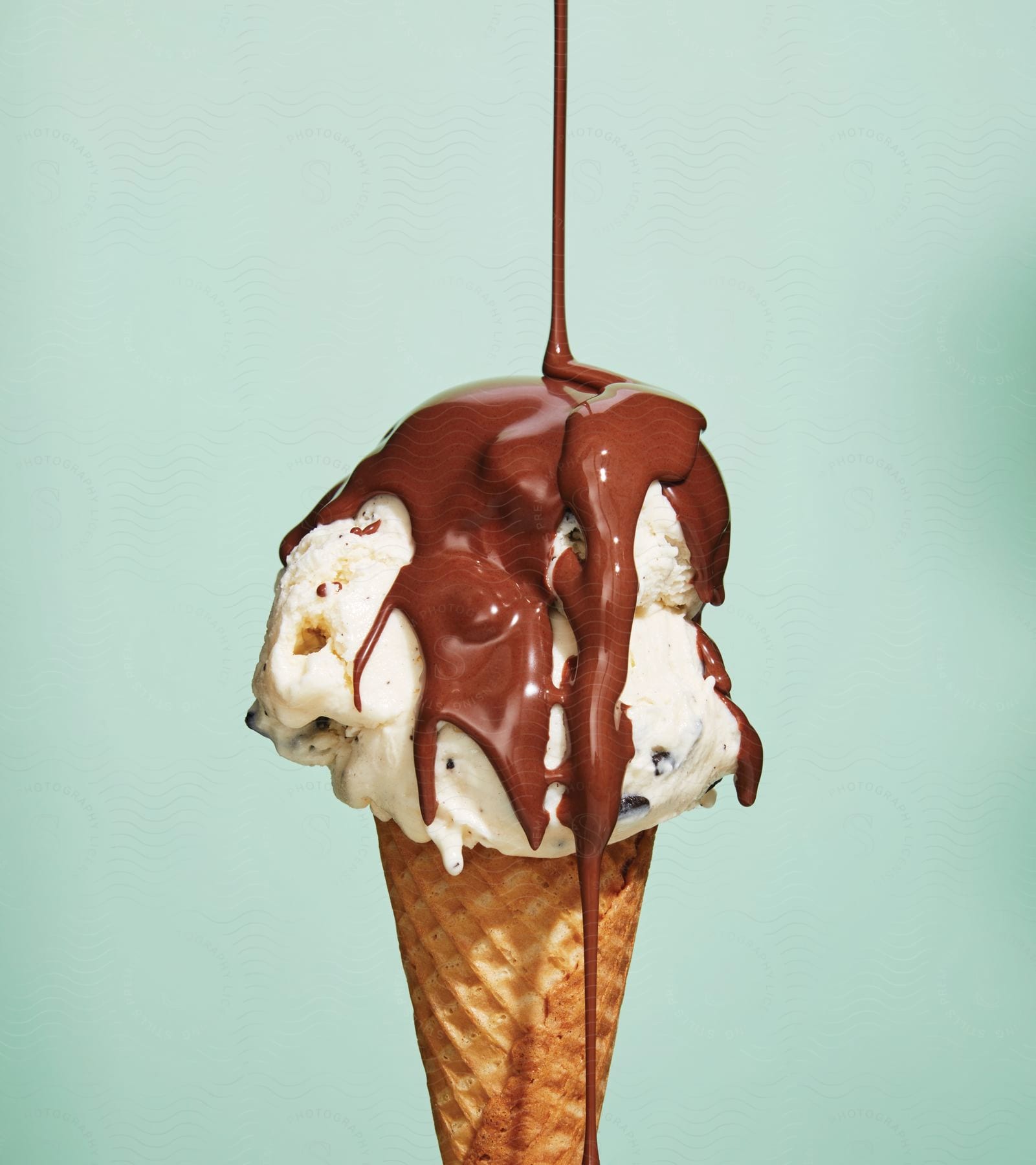 Chocolate syrup being poured over an ice cream cone