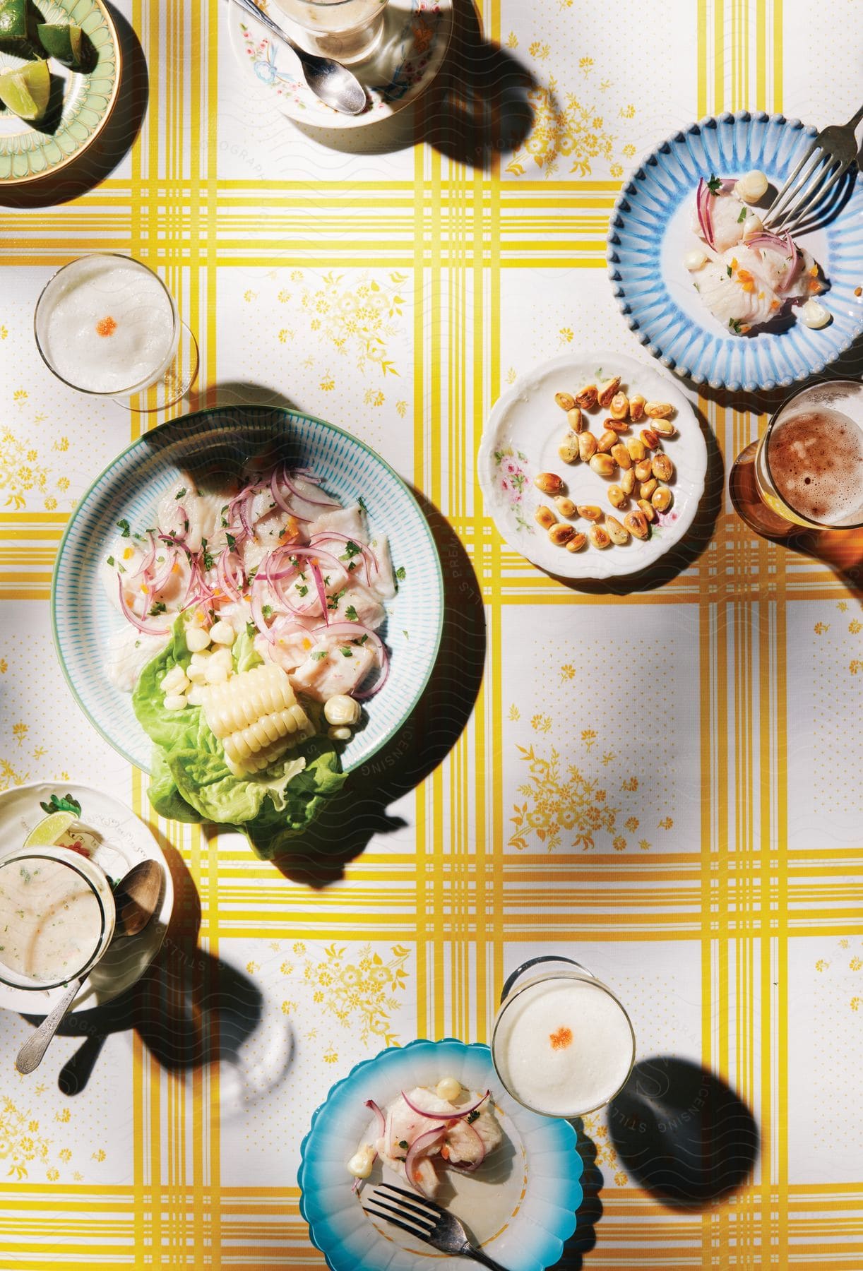 Various dishes beverages and cutlery are arranged artistically on a white and yellow tablecloth