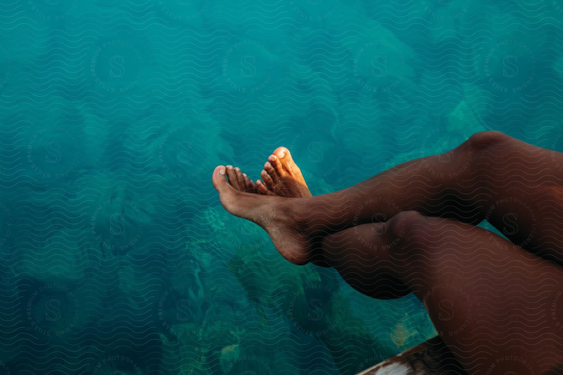 A body part is seen in a landscape with blue water