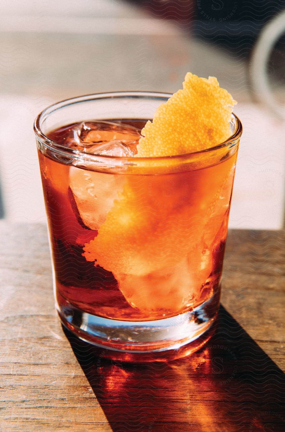 An iced drink with garnished orange peel is placed on furniture