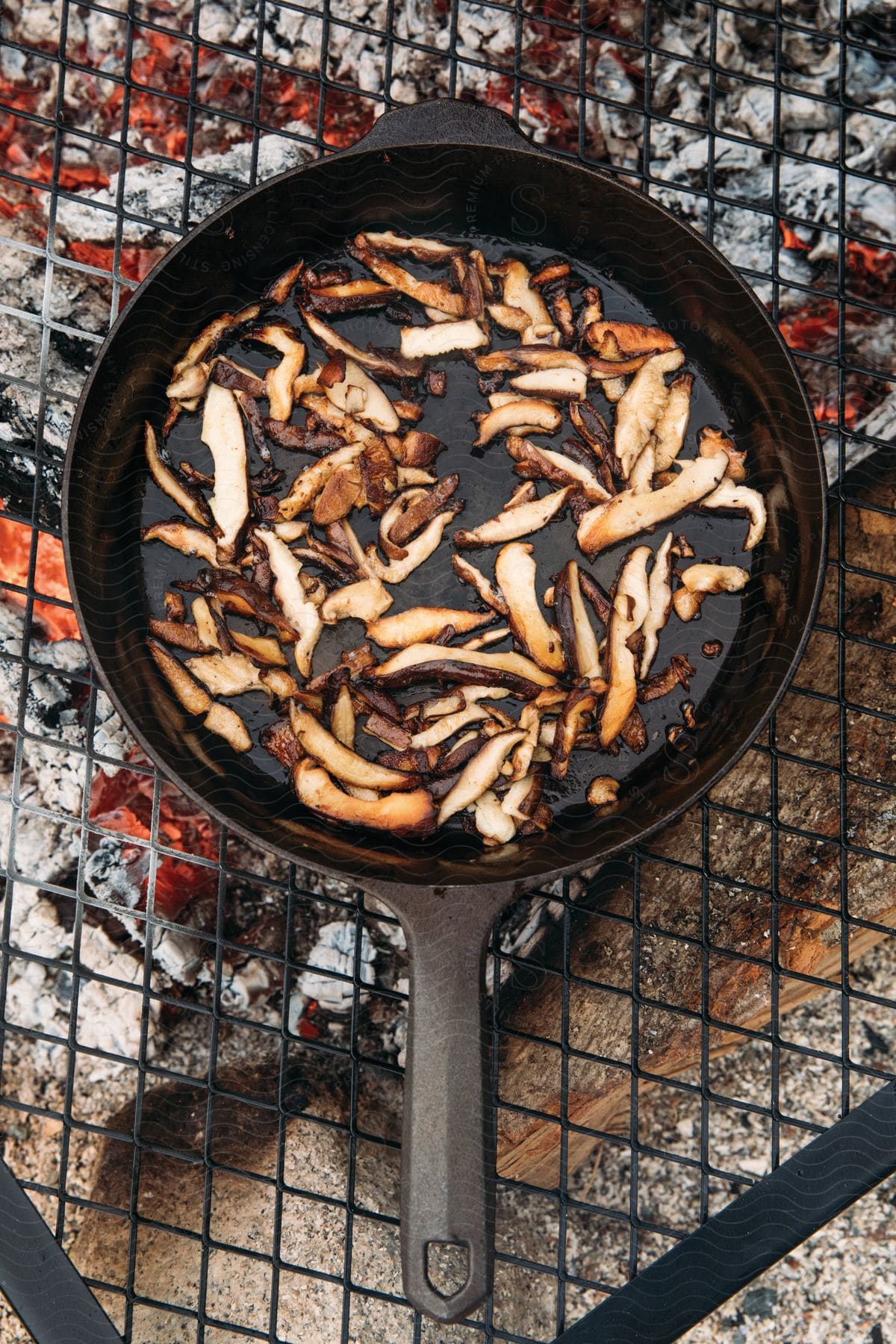 Food frying on a cast iron pan over a grill