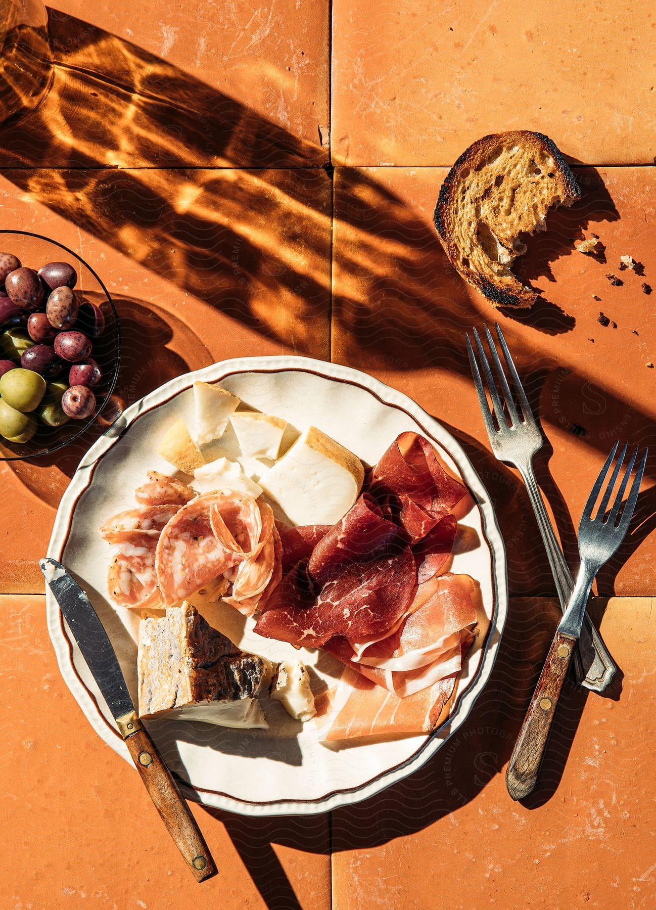 A breakfast meal consisting of fruits bread and a plate with two forks and a knife on top