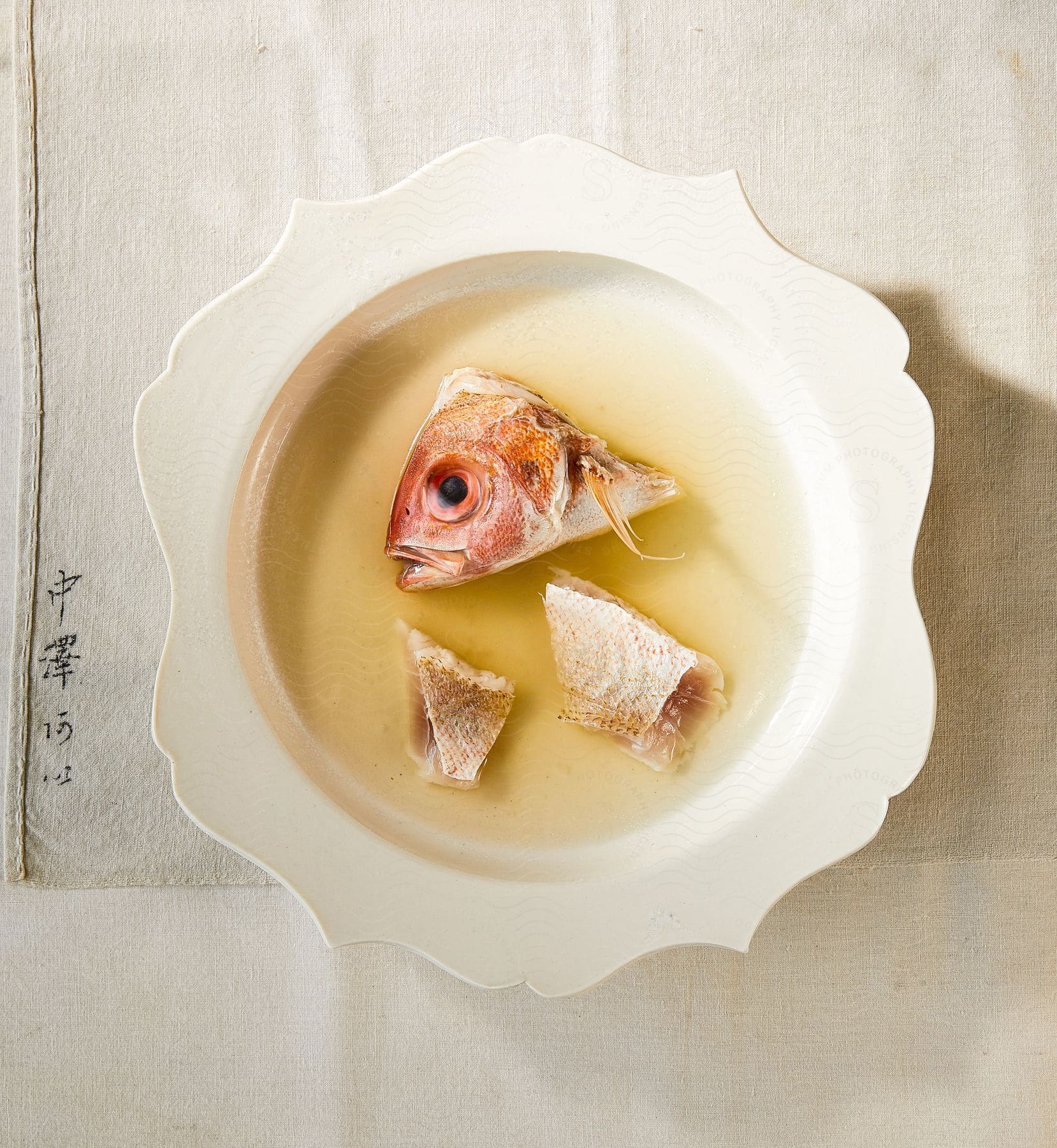 A white plate with fish and water on a stable surface