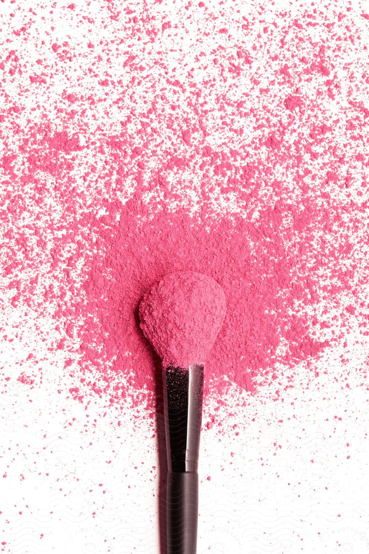 Close up of makeup brush with pink powder scattered