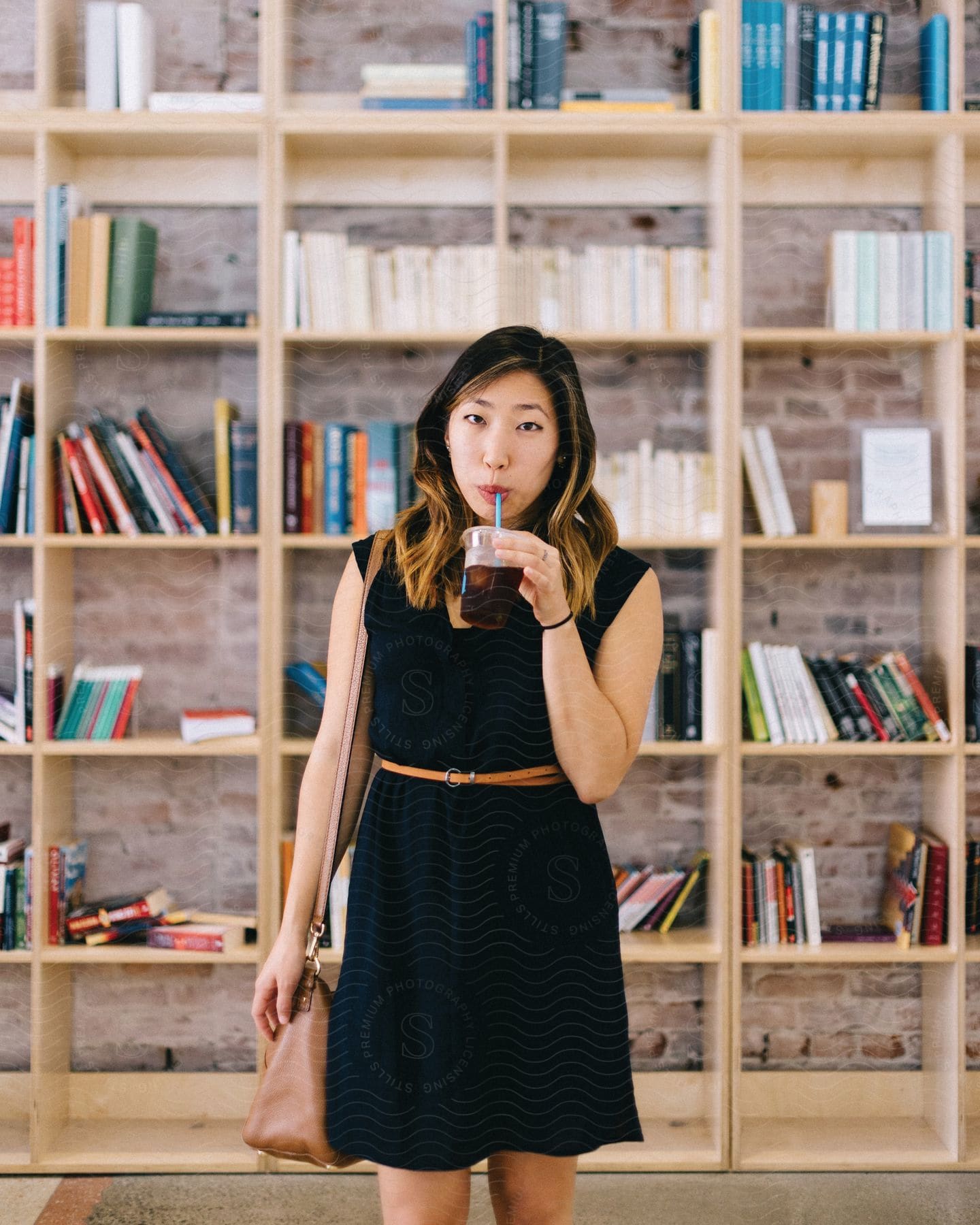 A woman holding a cup of iced coffee in a library