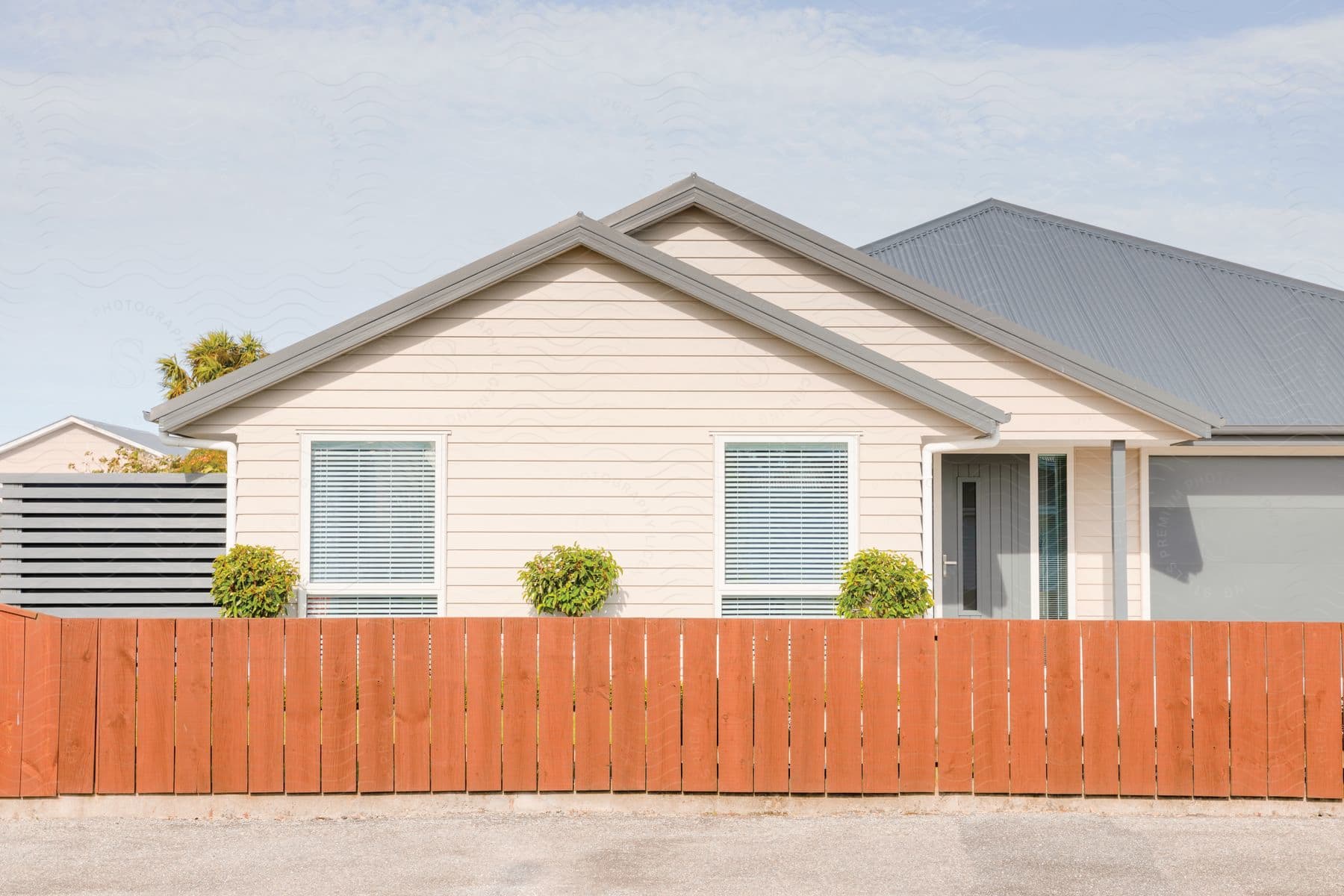 A pink house with a gray garage door is seen behind an orange fence