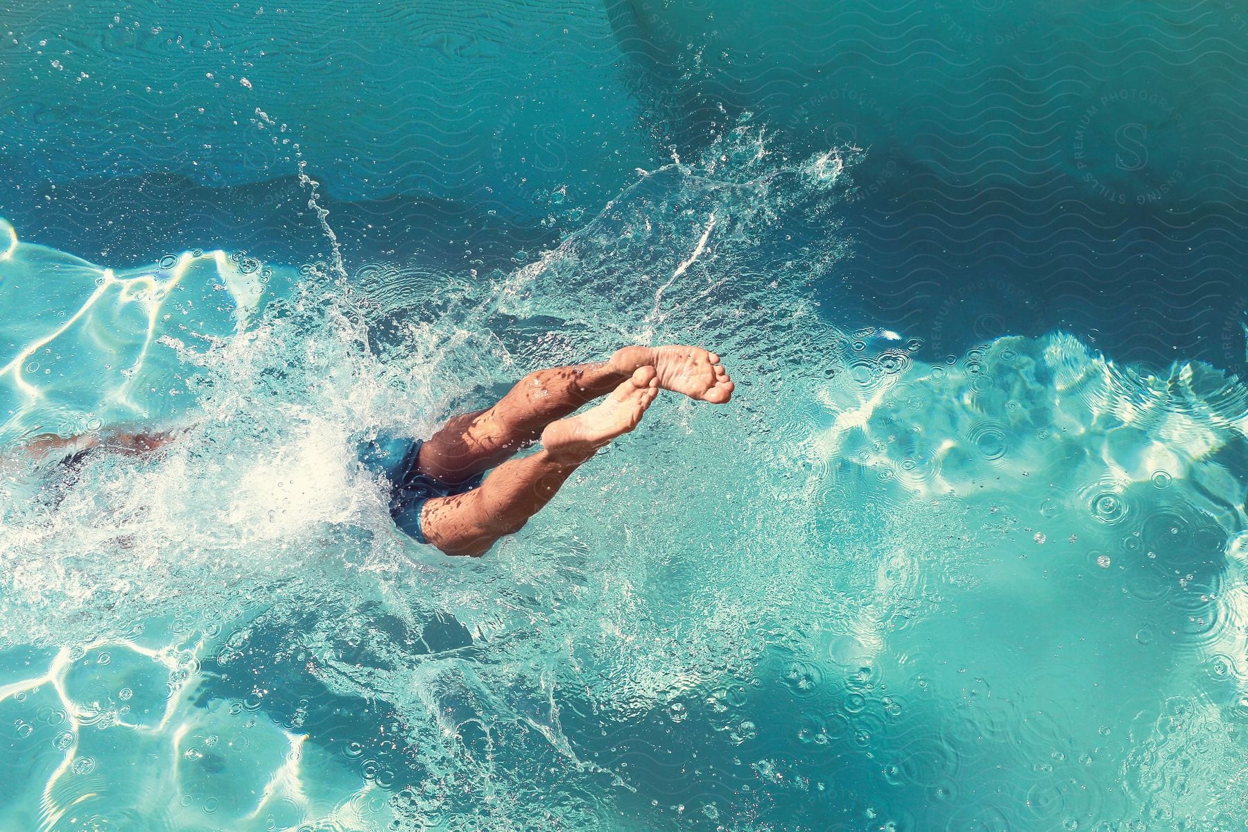 A man performs a dive in a swimming pool with his feet just above the waters surface