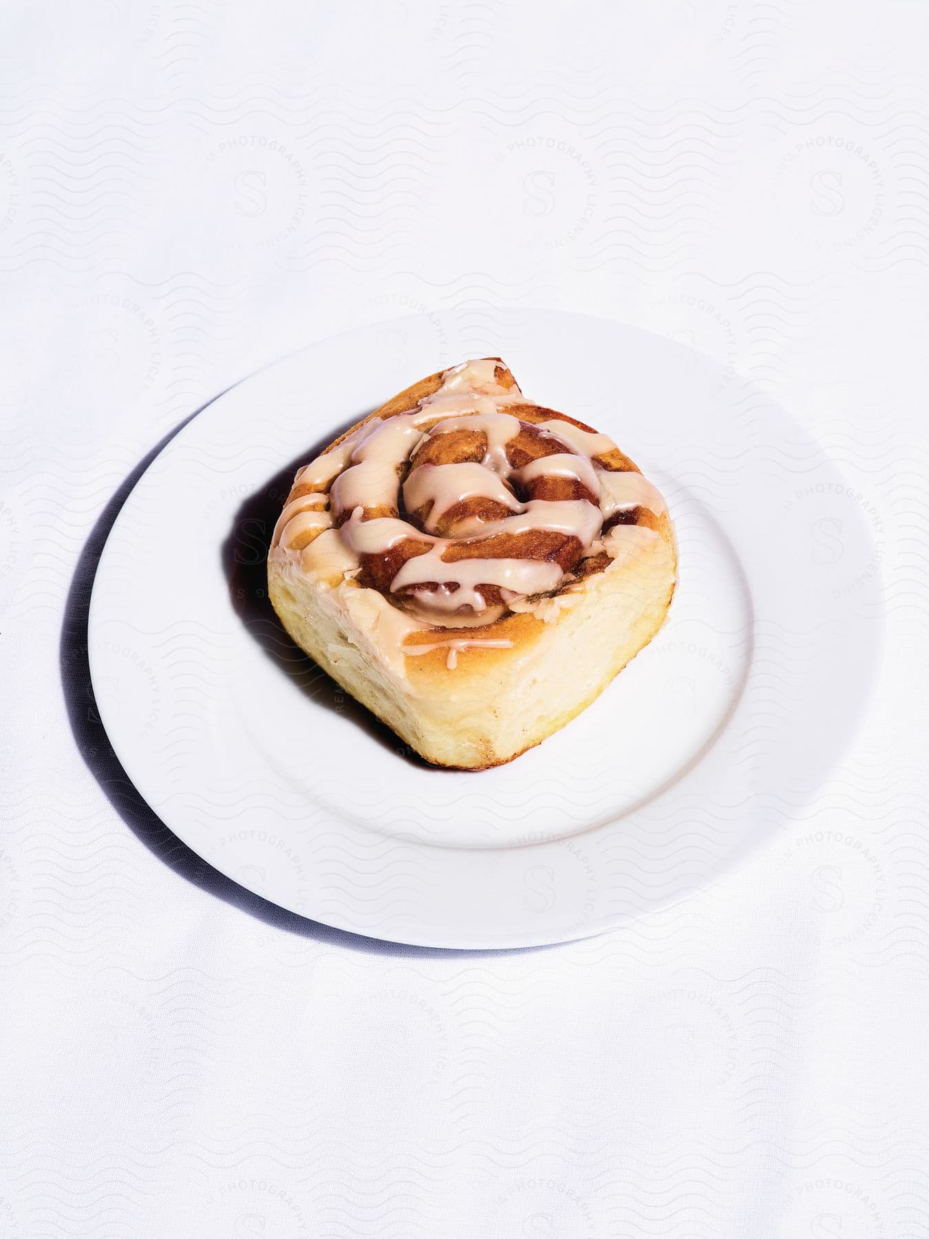 A cinnamon roll with icing on a plate