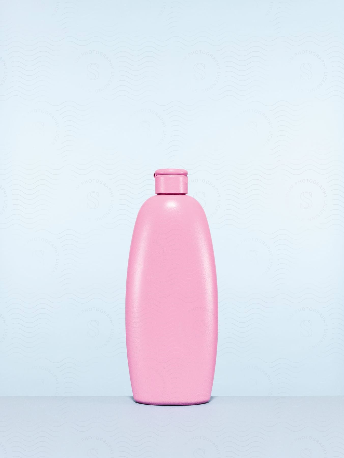 A pink plastic bottle on a grey surface with a pale grey background