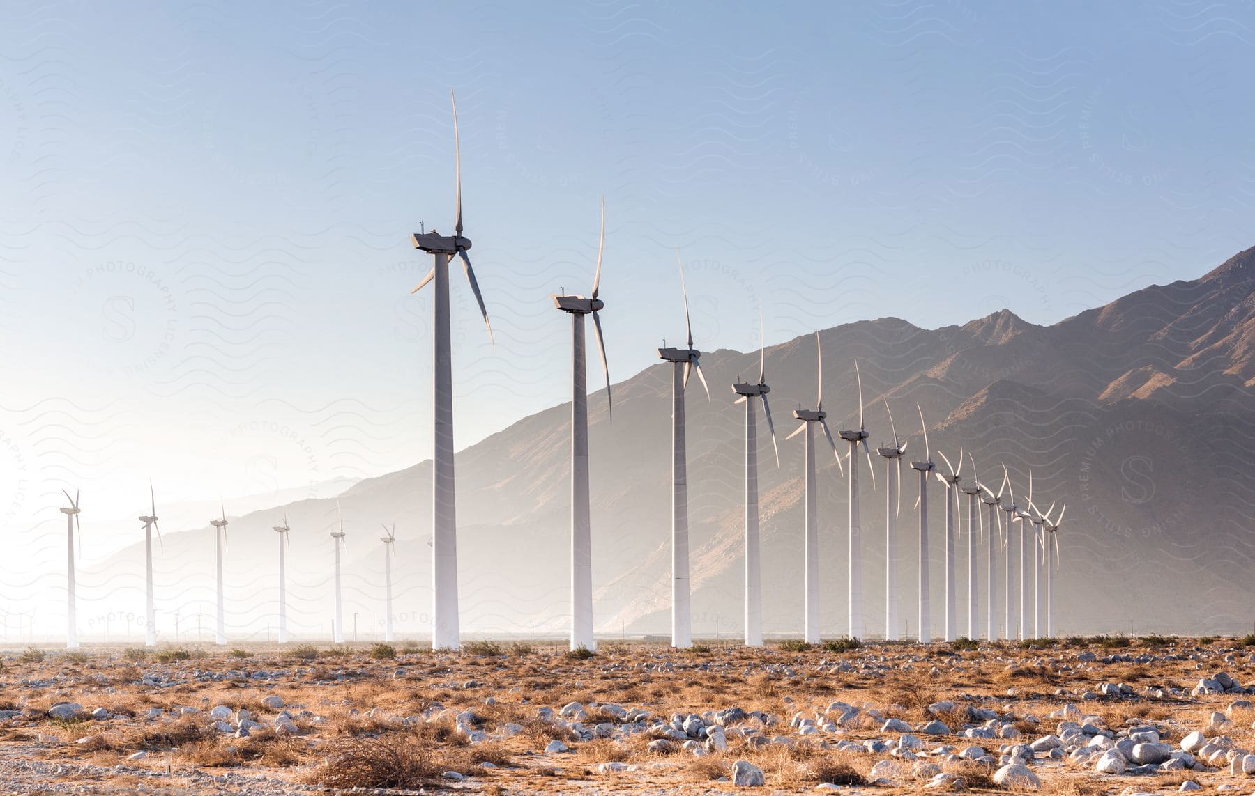 Stock photo of wind turbines spin alongside a mountain range