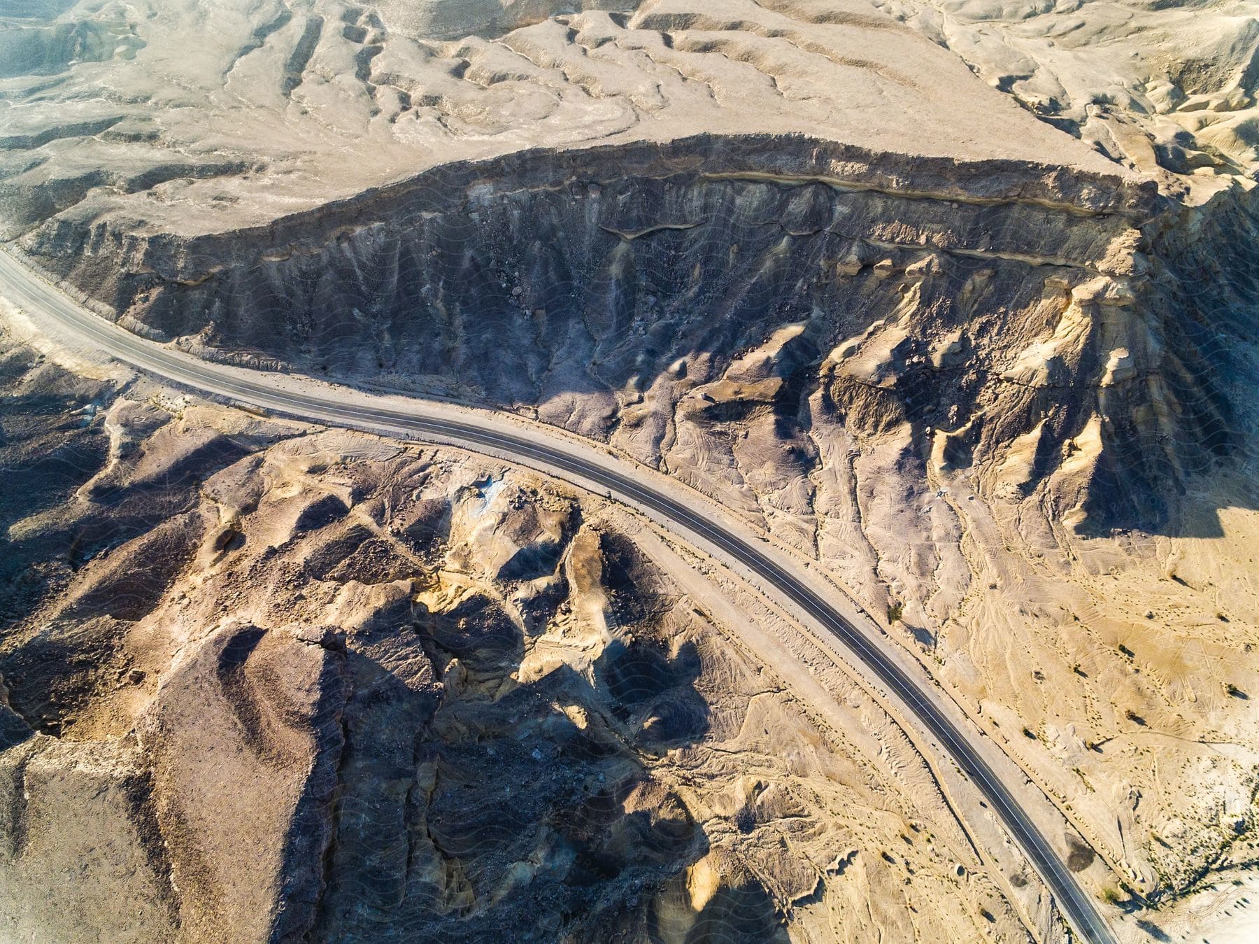 A long road runs through the desert among rock formations and canyons