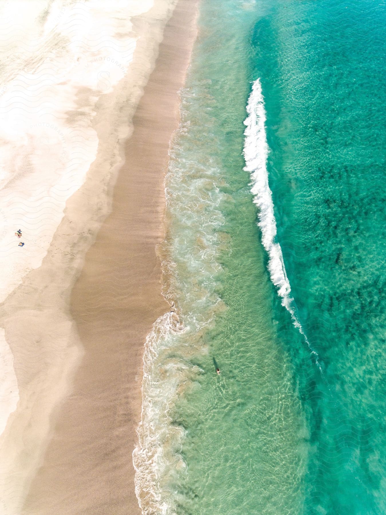 A lifeguard watches as a man walks into the water and waves roll into shore on a beach