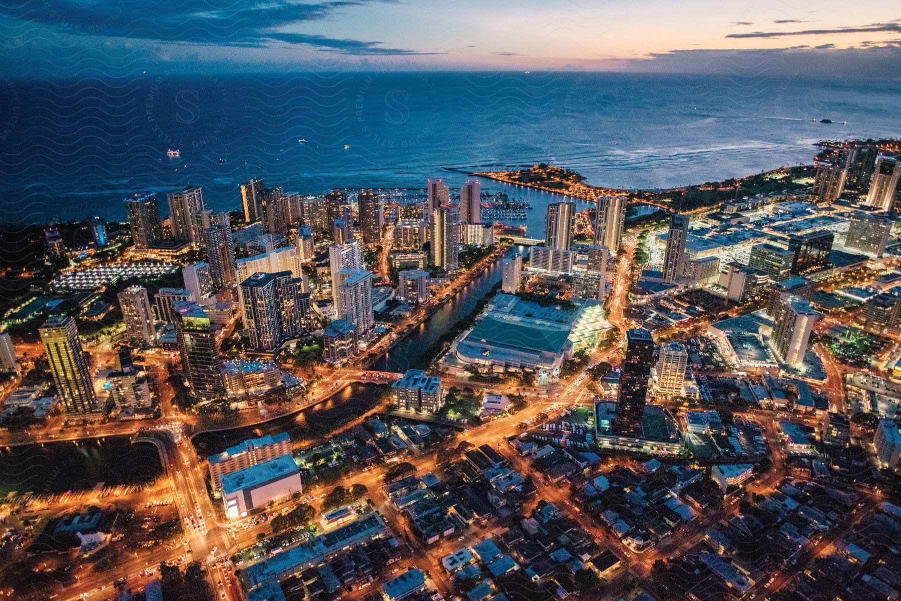 A coastal city at dawn surrounded by water with a skyline dominated by highrise buildings and skyscrapers