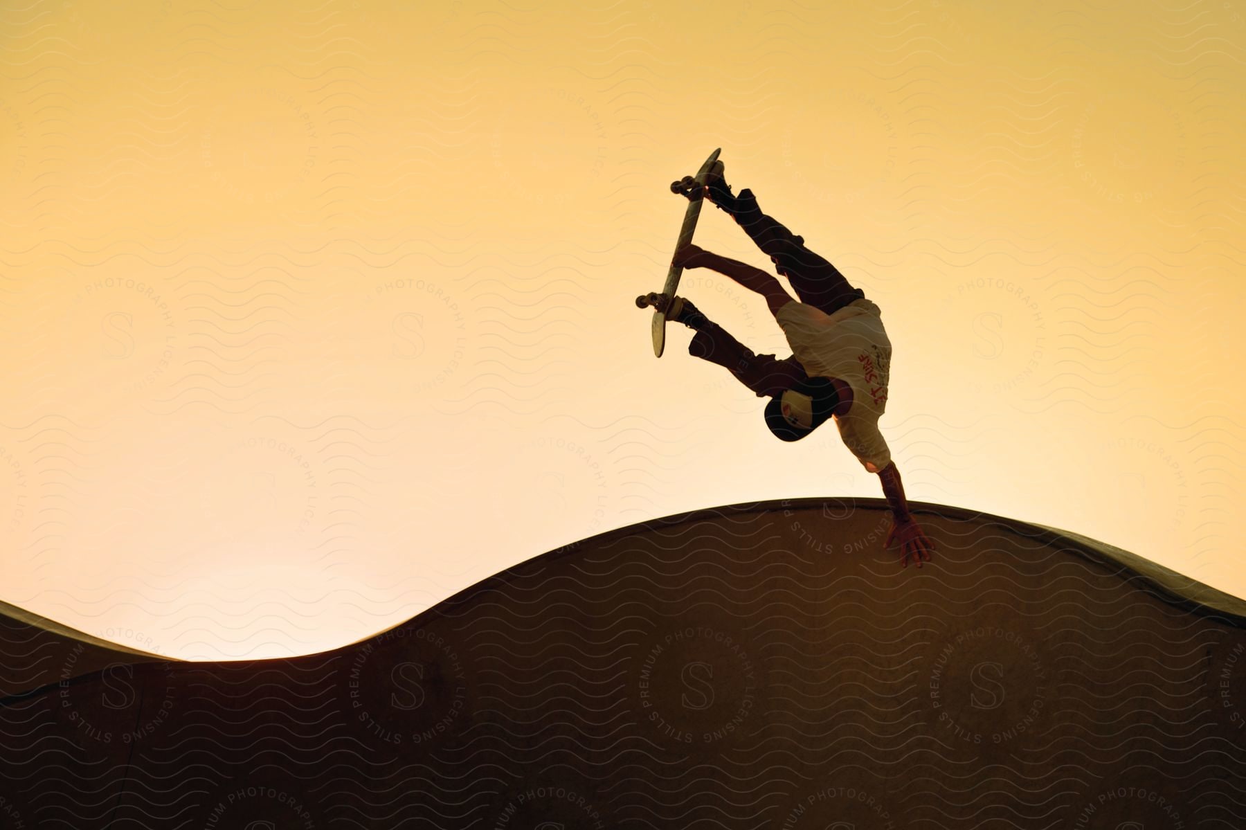 A person performing skateboard tricks on a ramp outdoors at dusk or dawn