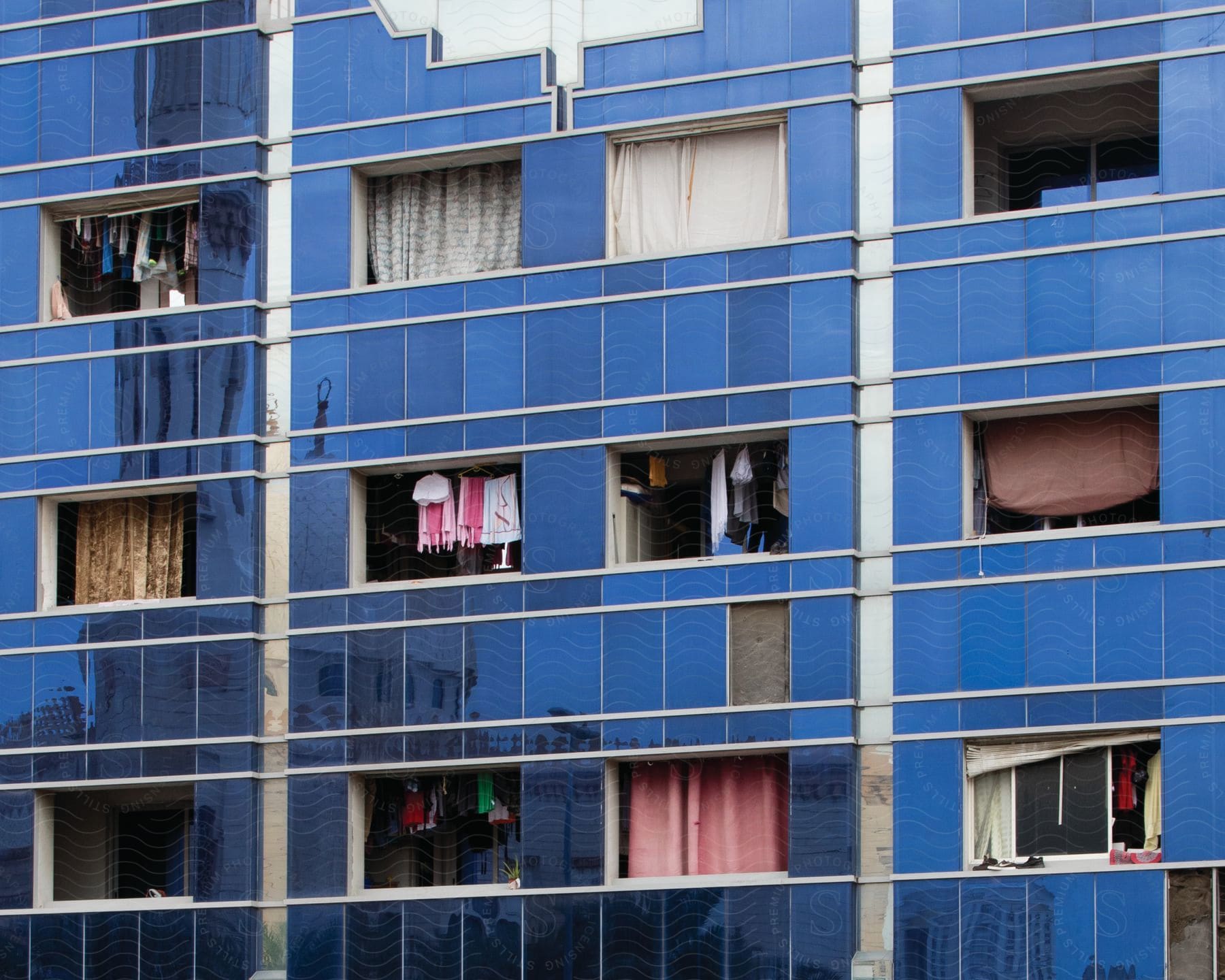 A blue condominium building with open windows