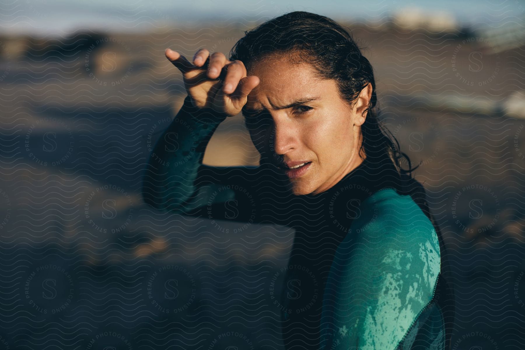 A woman wearing a wet suit looks nervous at the beach