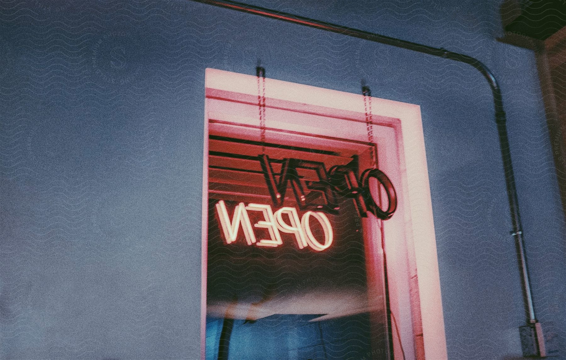 Shop window reflects neon open sign at night