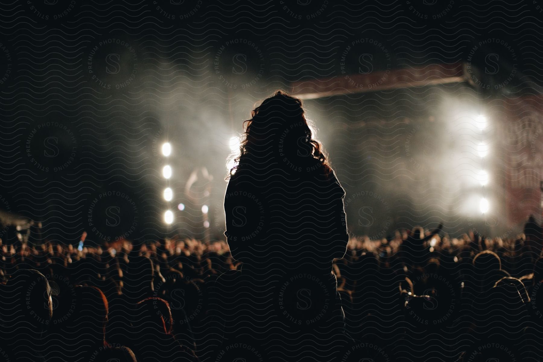 A large crowd stands in front of a concert stage at night