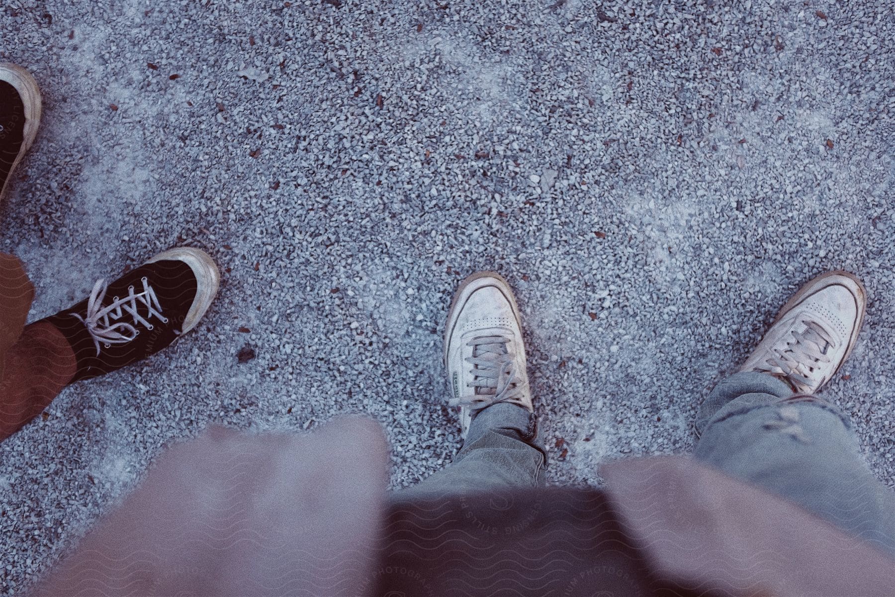 Two men wearing sneakers jeans and shorts stand on the ground