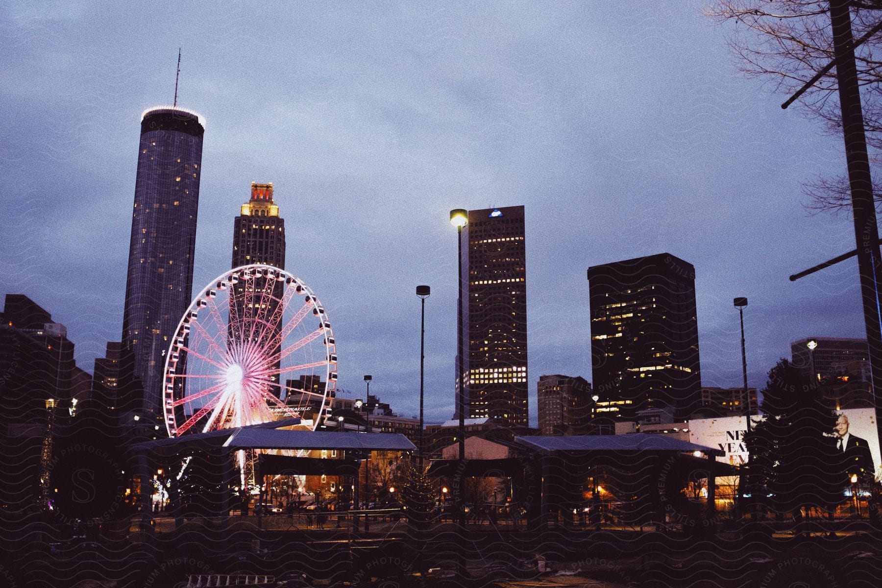 A cityscape at dusk with a skyscraper and a ferris wheel in the background