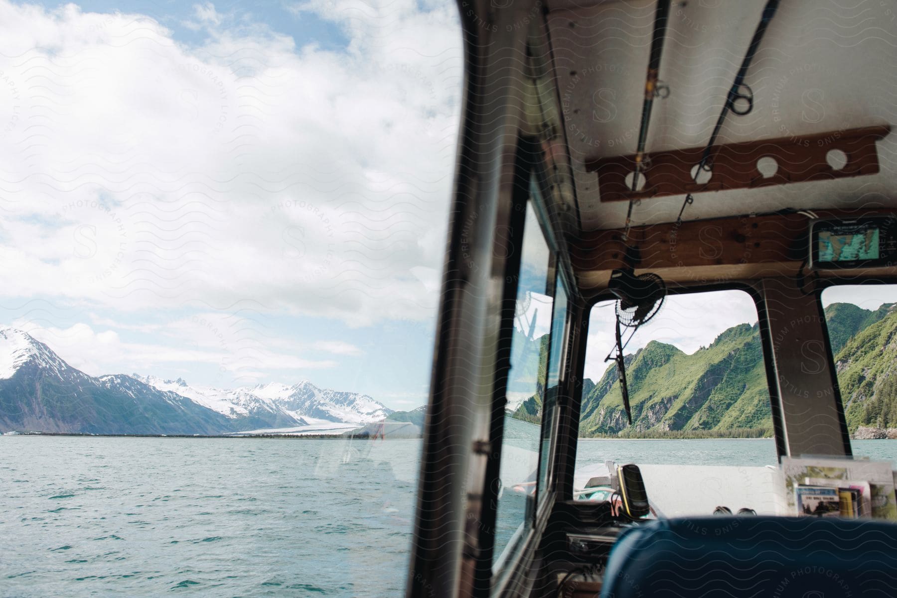 A Boat With Snow Covered Mountains And Moss Covered Hills In The Background On A Sunny Day