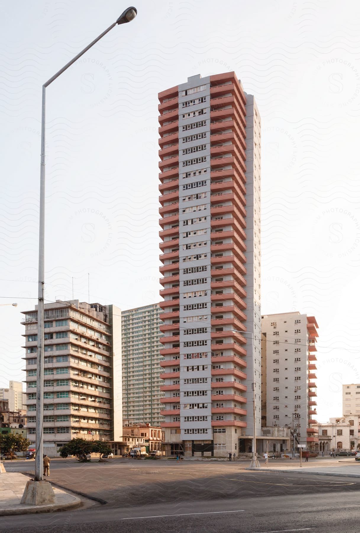 Modern high rise apartment tower in the city with red lined sections separating floors on a cloudy day