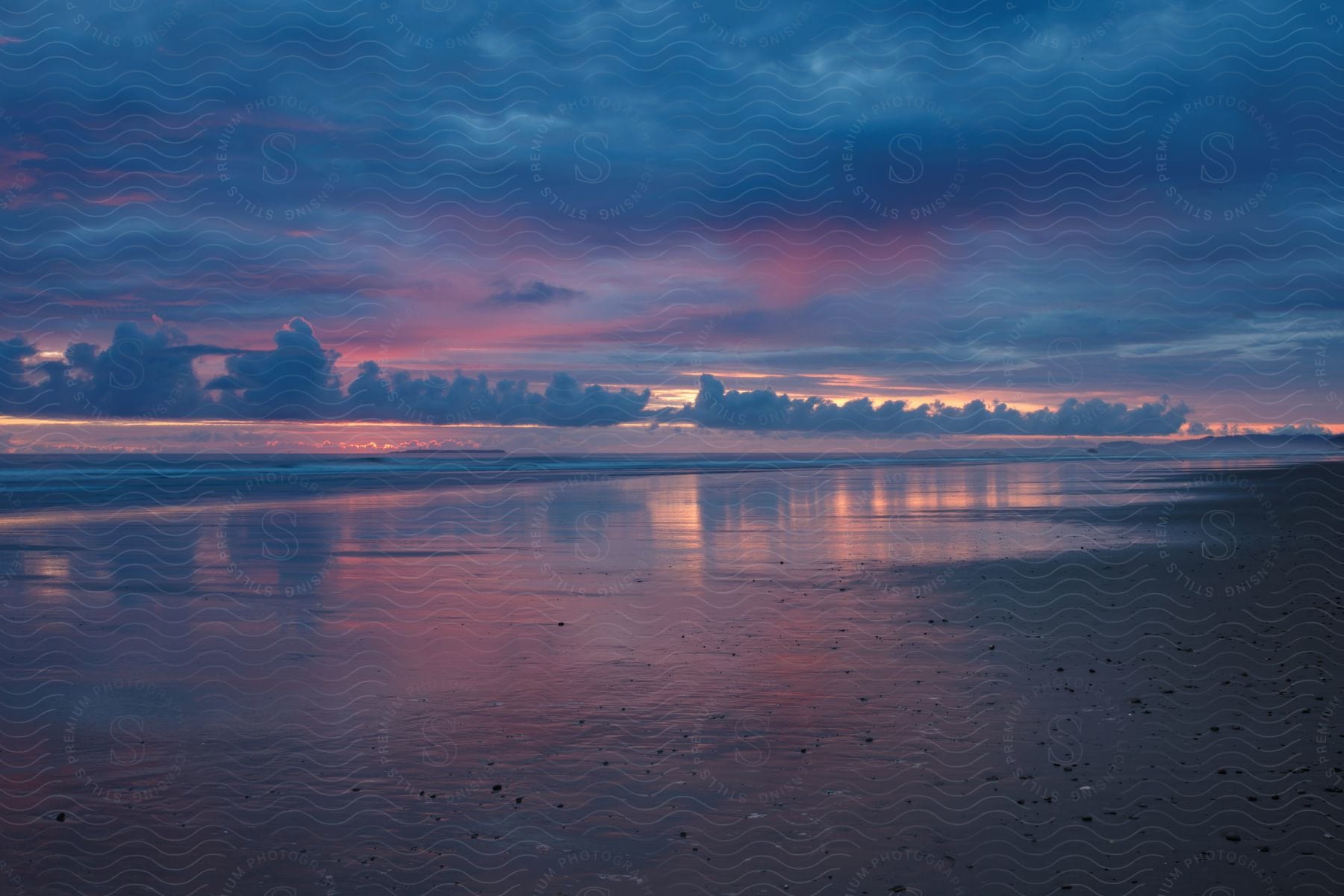 The sun is setting above the beach horizon