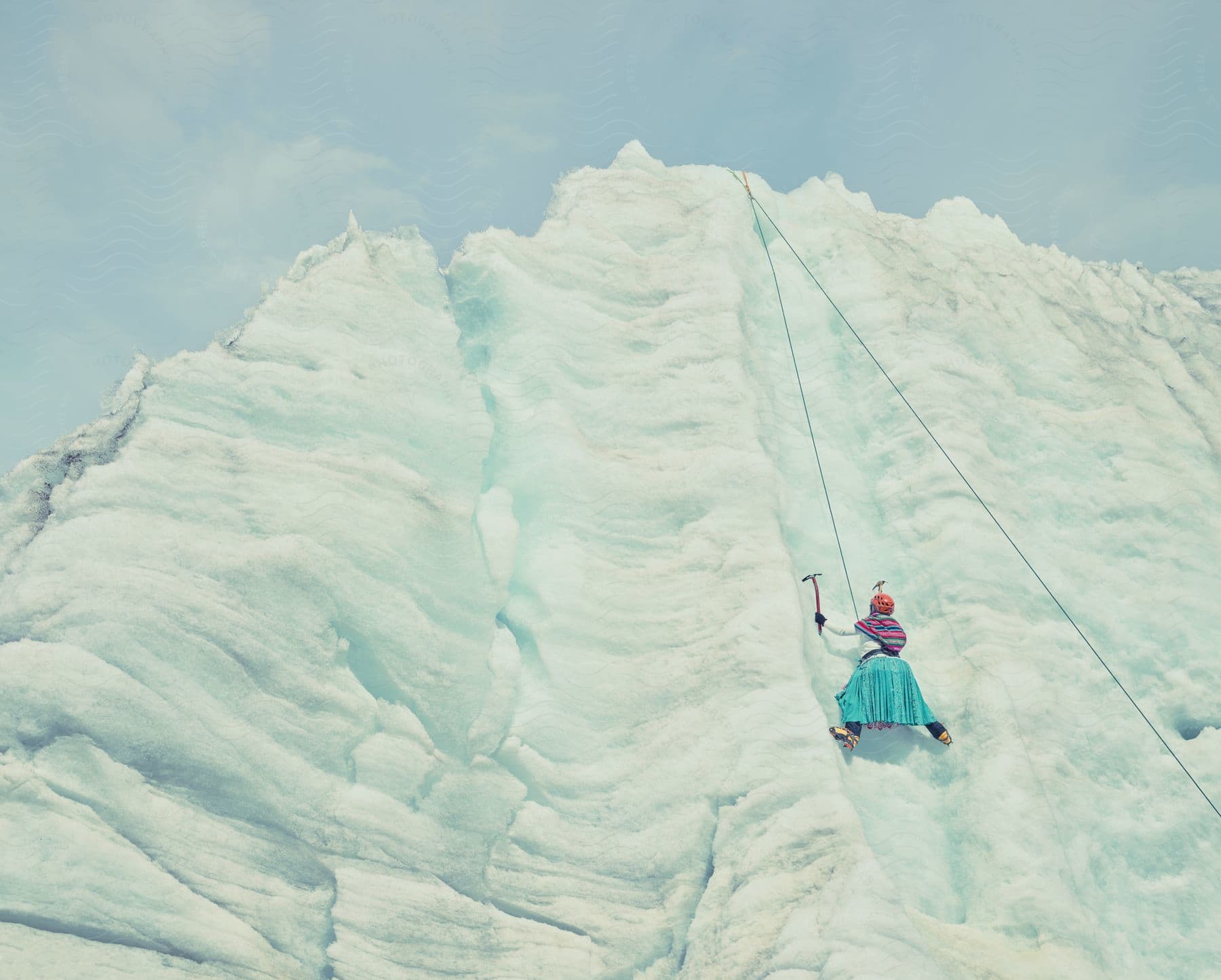 A female ice climber with ice picks on an ice wall during the day