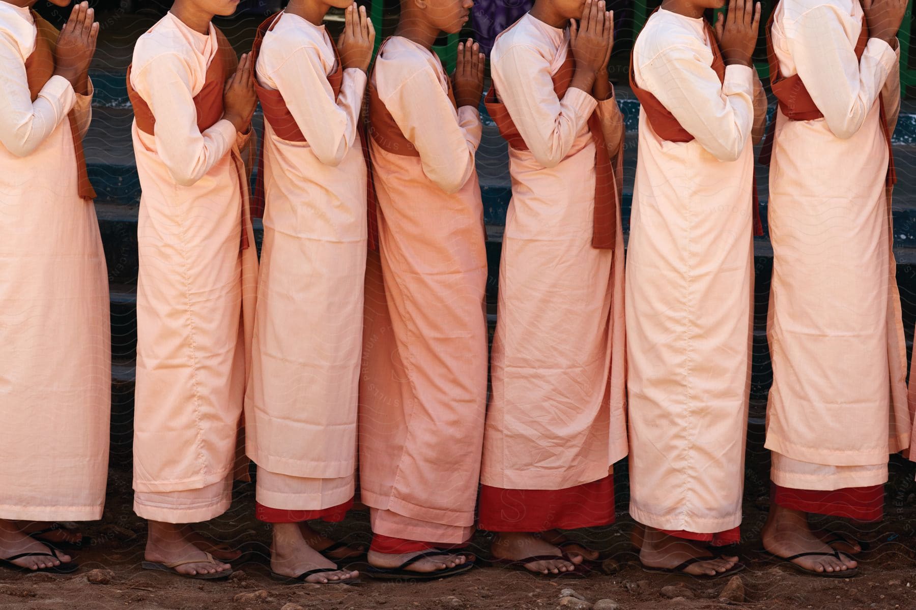 Boys in robes stand praying in sandals