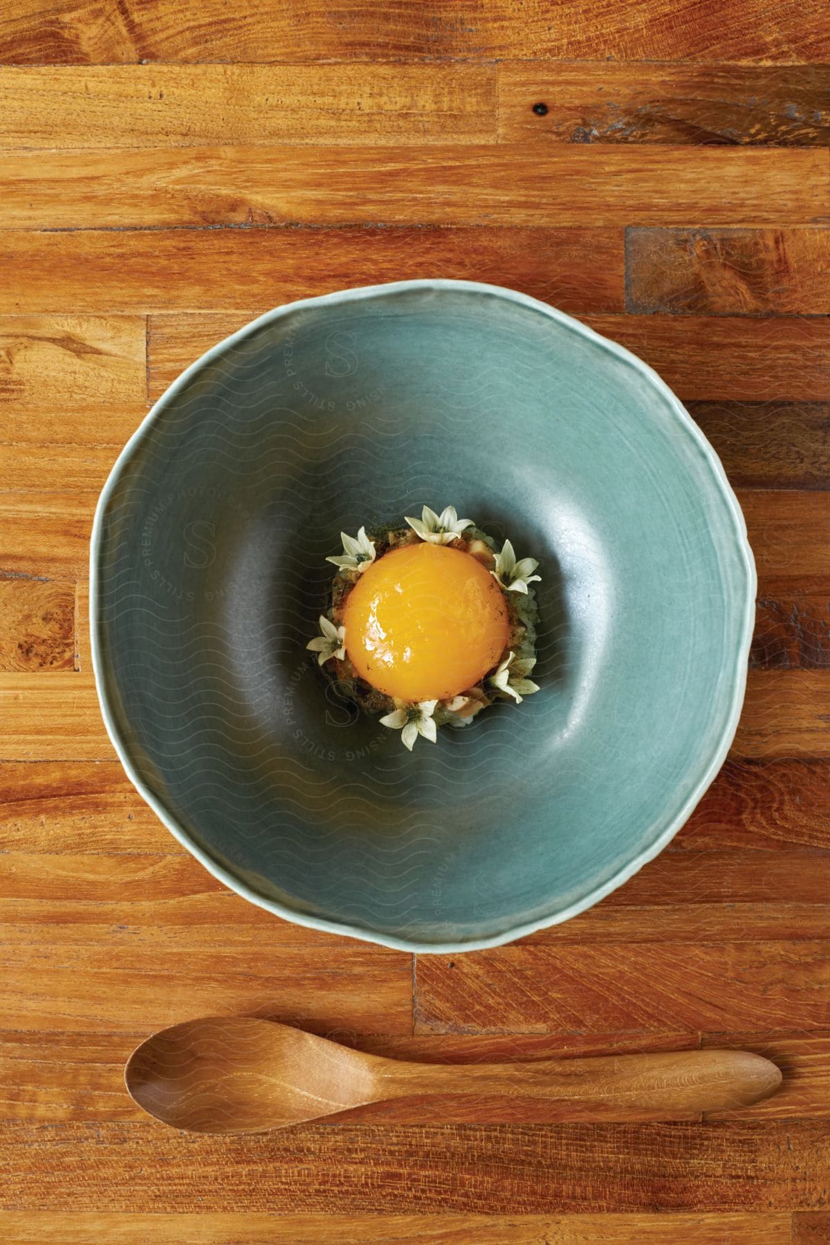 A decorated egg yolk in a bowl with a wooden spoon on a wooden table