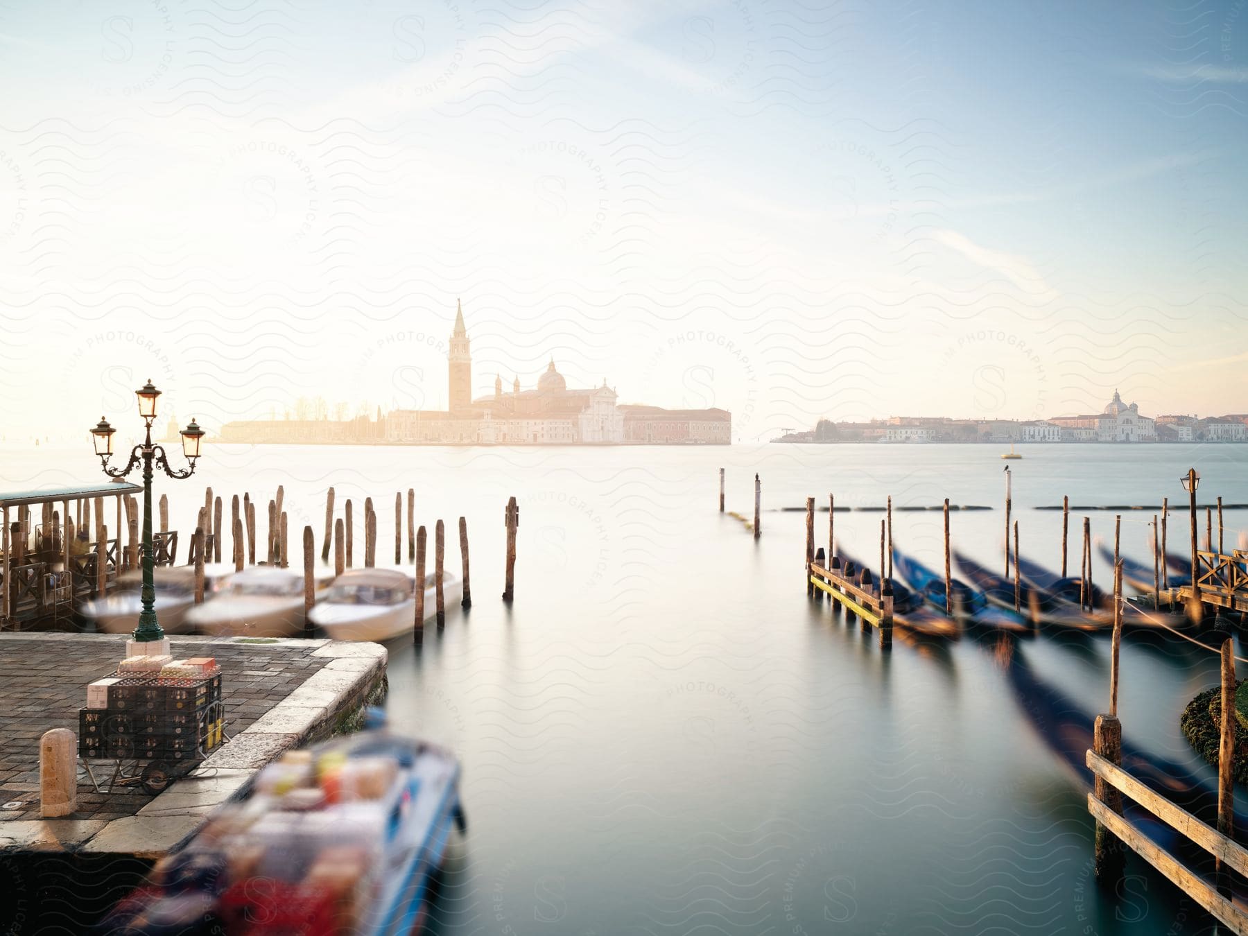 Gondolas and boats moored to a pier across a canal from a church