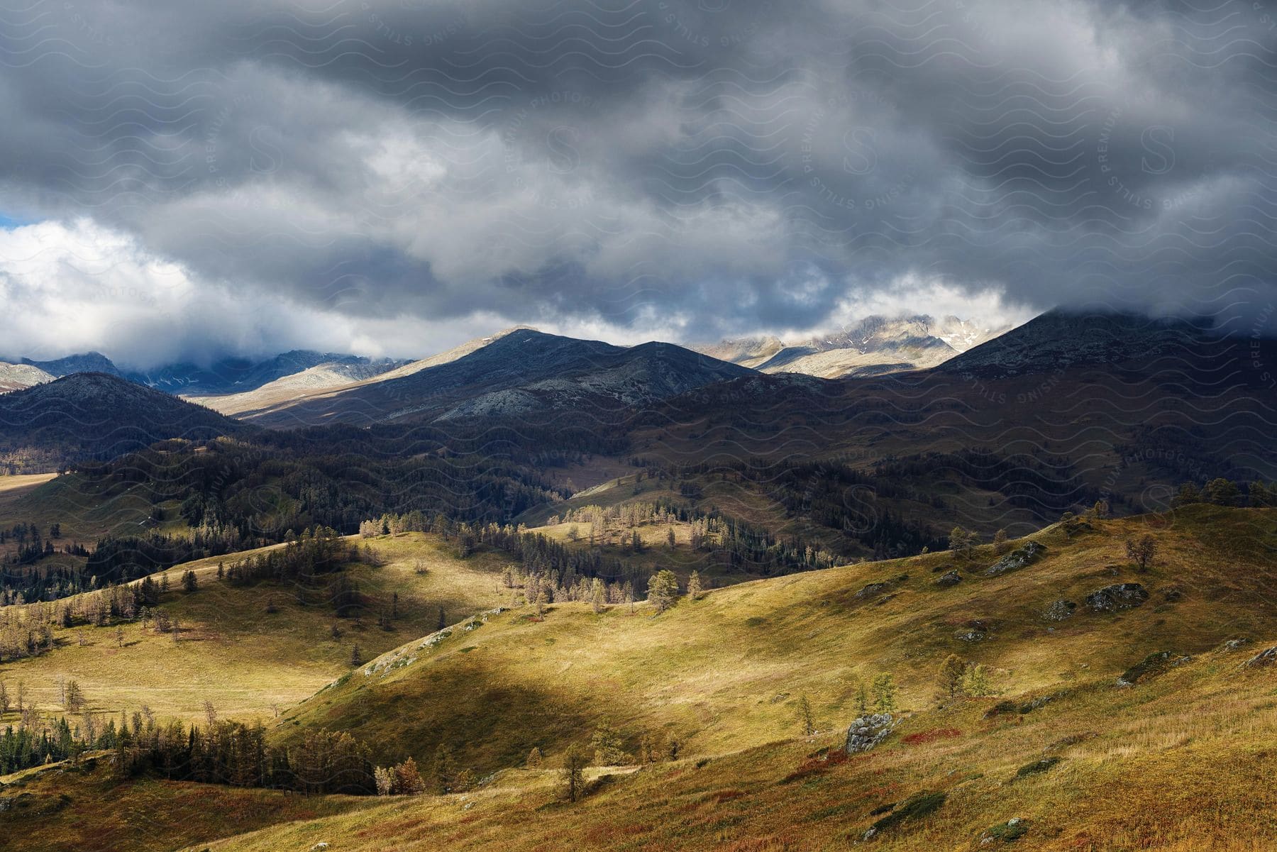 Sunlight peaks through dense clouds over rolling hills