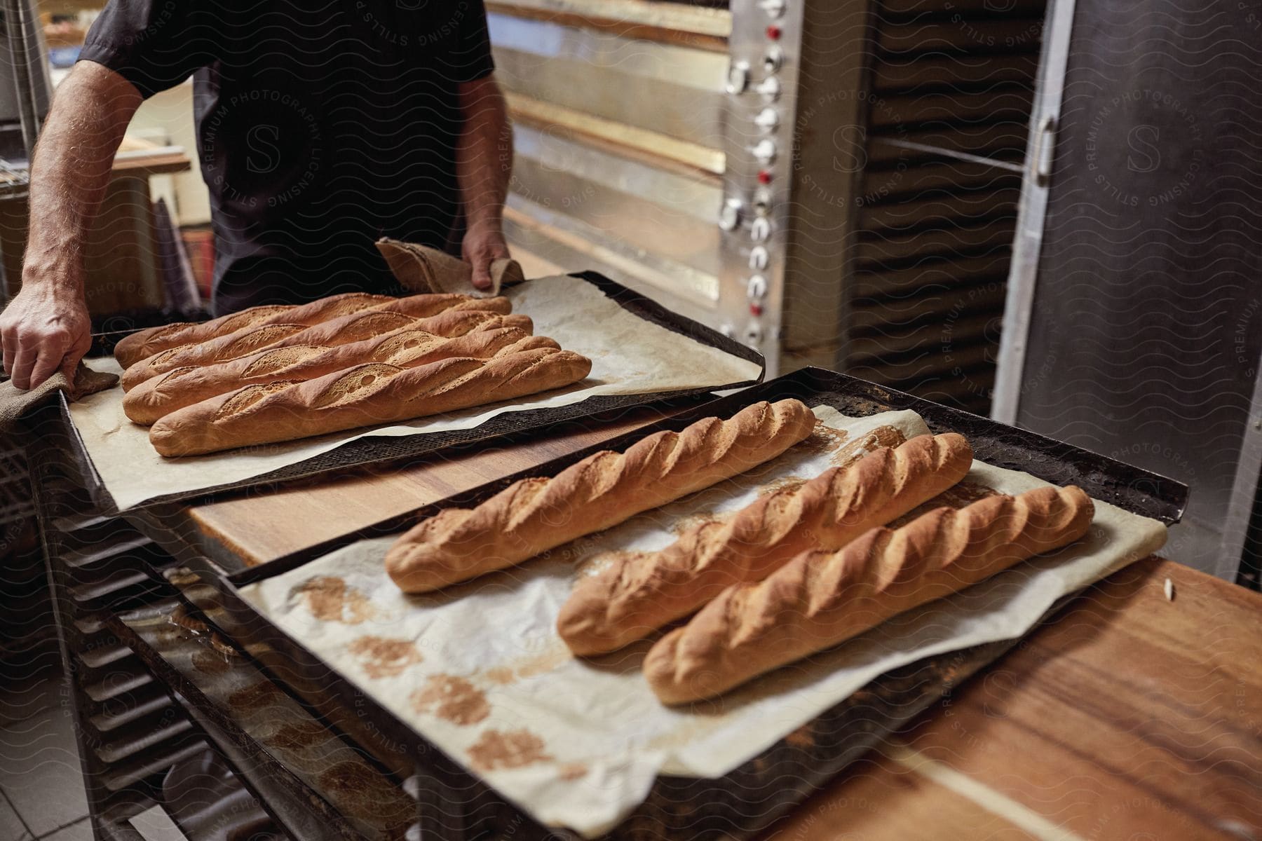 A Baker Removes Cooked Baguettes From The Oven