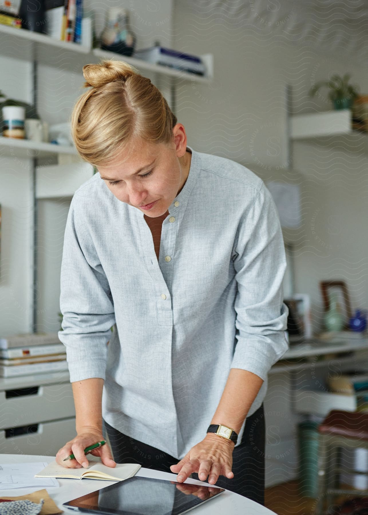 A woman taking notes from an ipad on a coffee table in an office