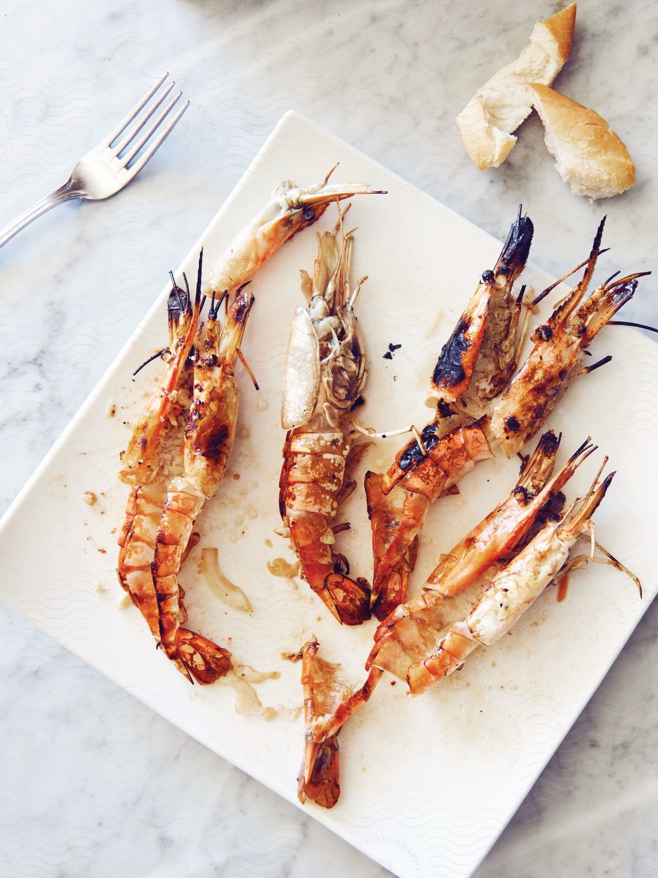 Grilled prawns on a plate with a fork and bread
