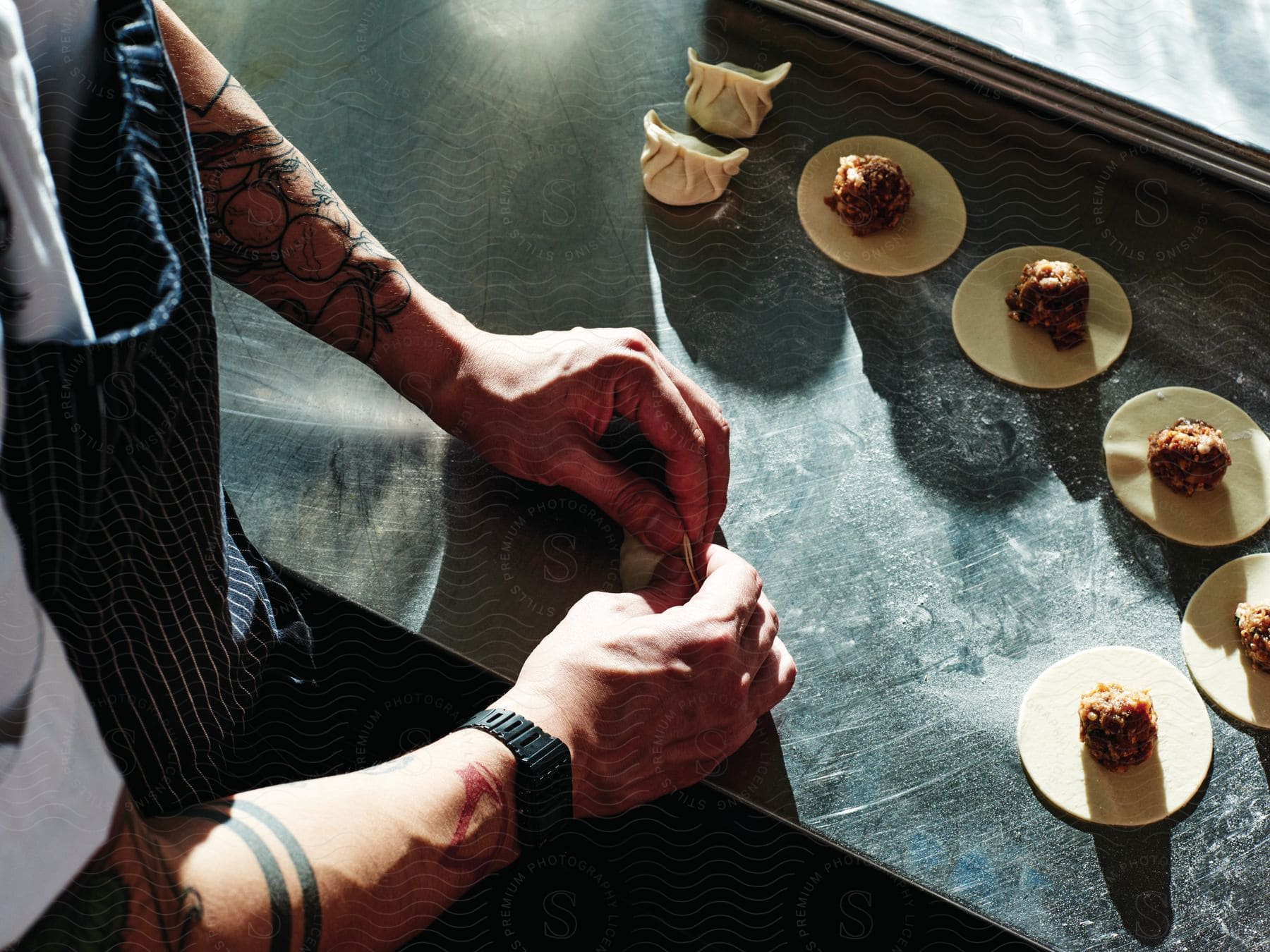 A chef prepares dumplings using pastry and meat