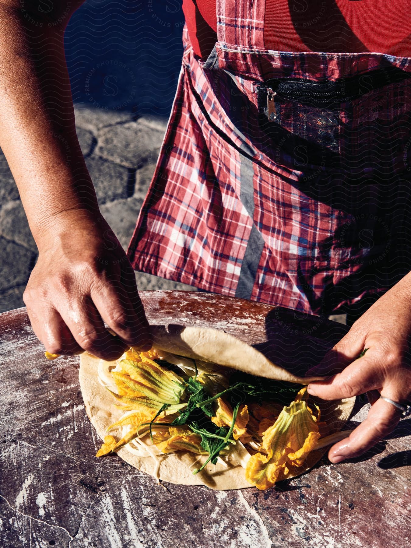 Stock photo of man rolling a wrap over flowers and herbs