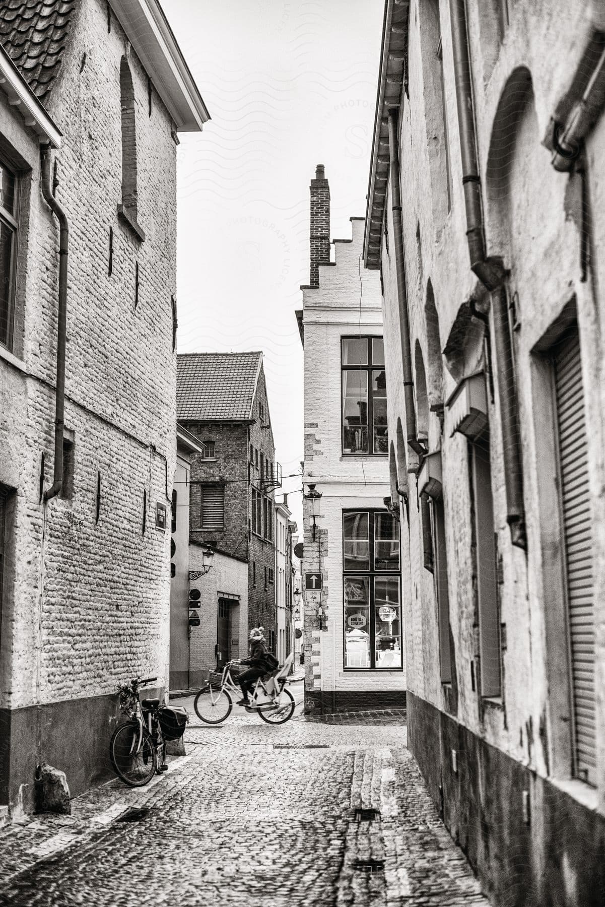 An alley in a town in the netherlands with a person riding a bicycle on cobblestone roads