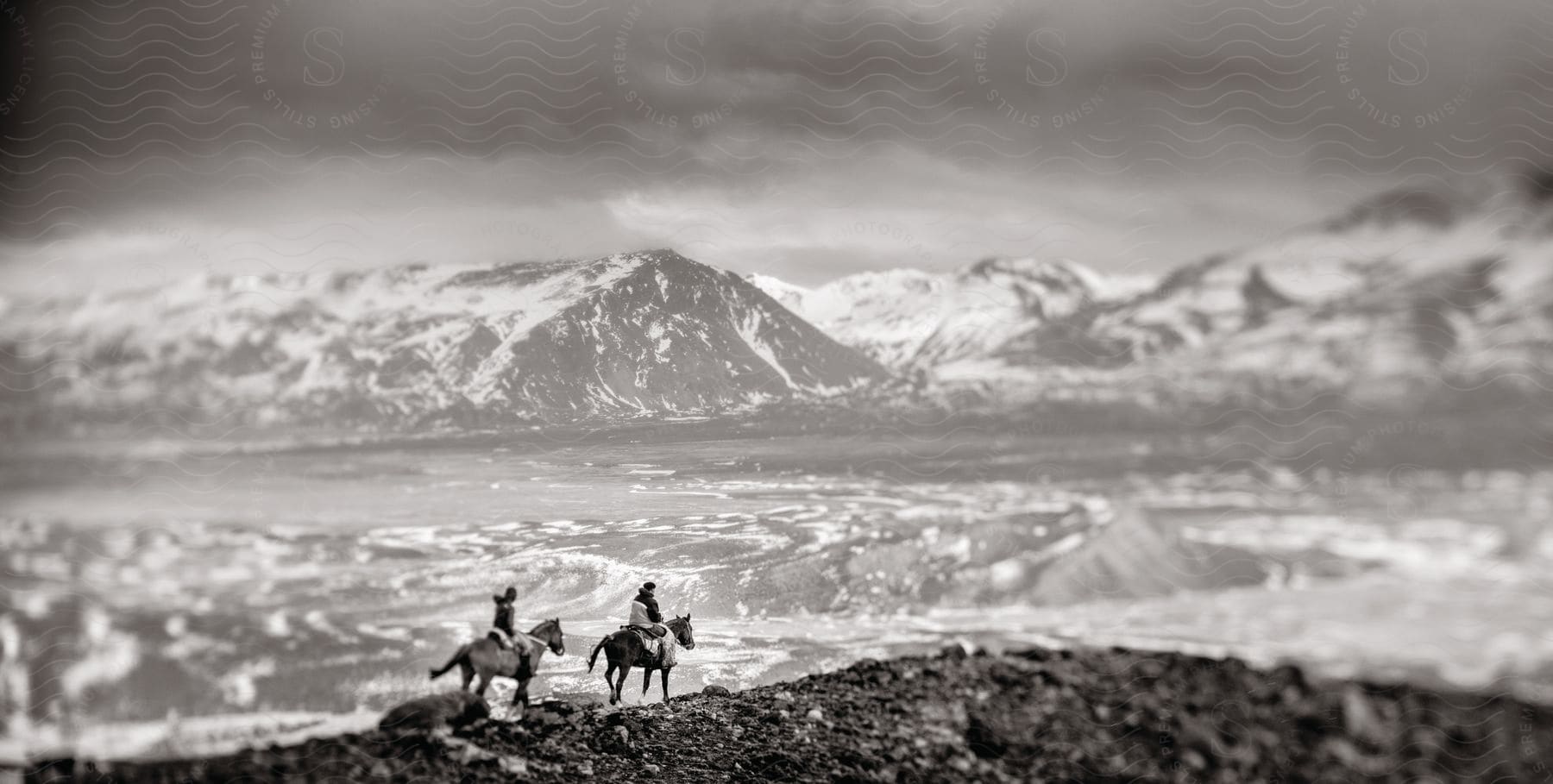 Two people on horseback crossing a mountain range